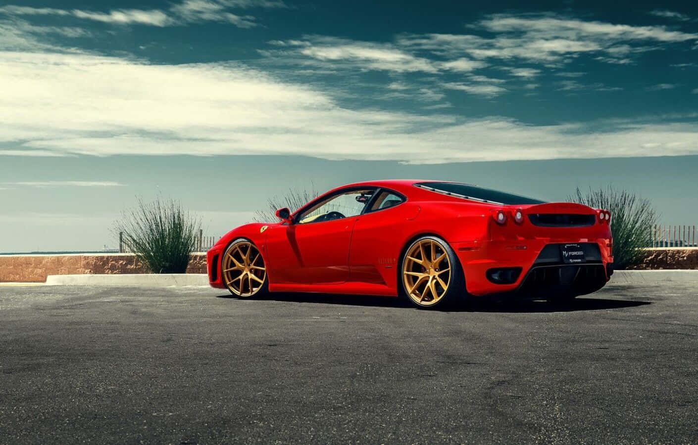 Ferrari F430 桌布 壁紙 — 一輛鮮紅色法拉利跑車配金色輪圈，停在陰天天空下的瀝青路面上。