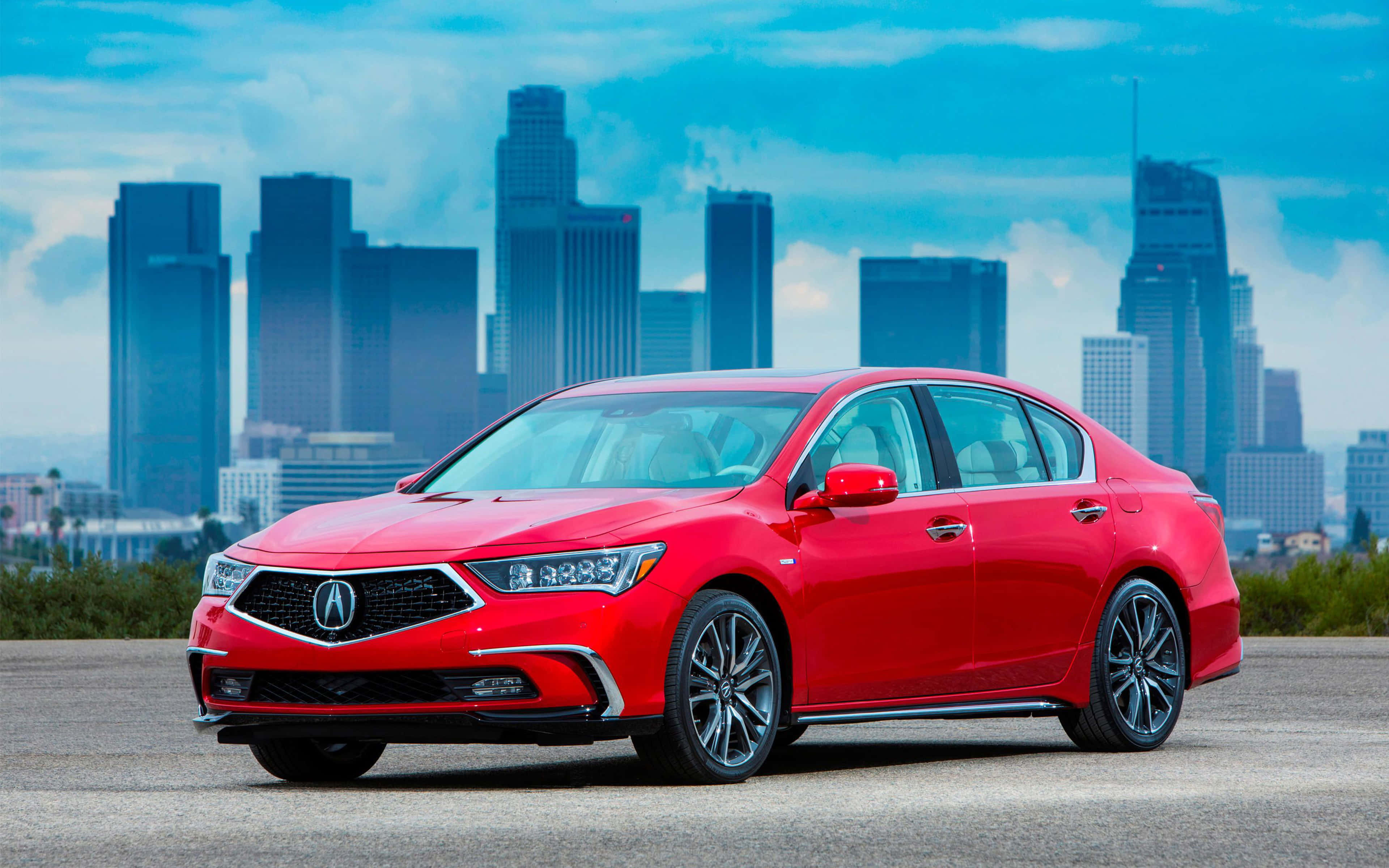 Acura Rlx 桌布 壁紙 — 一輛鮮紅色的Acura轎車在日光下閃閃發光，背景是高聳的城市摩天大樓和部分多雲的藍天。