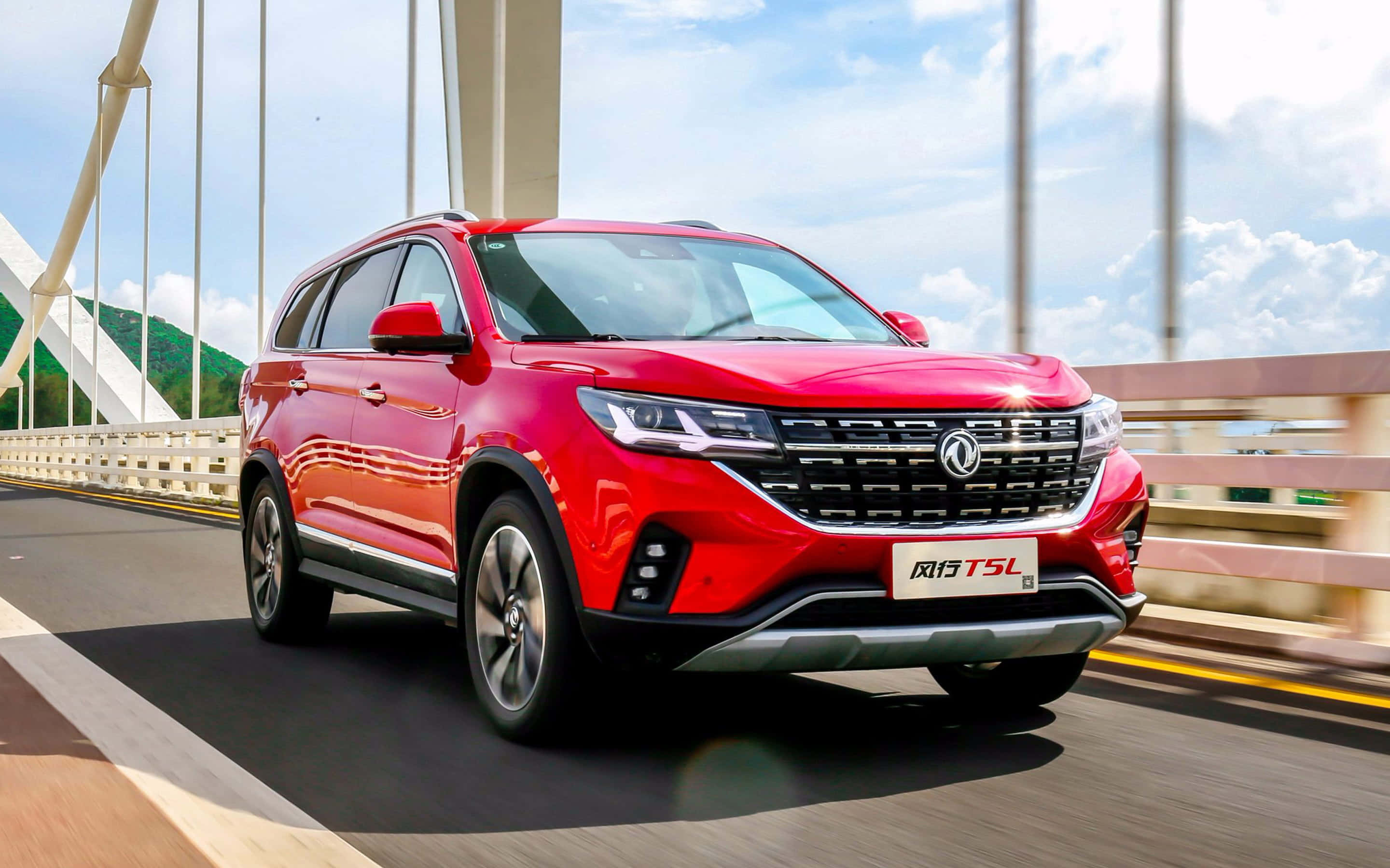 Dongfeng 桌布 壁紙 — 一輛鮮紅色的Fengxing T5L SUV在晴朗藍天白雲下，動態地行駛在現代斜拉橋上。