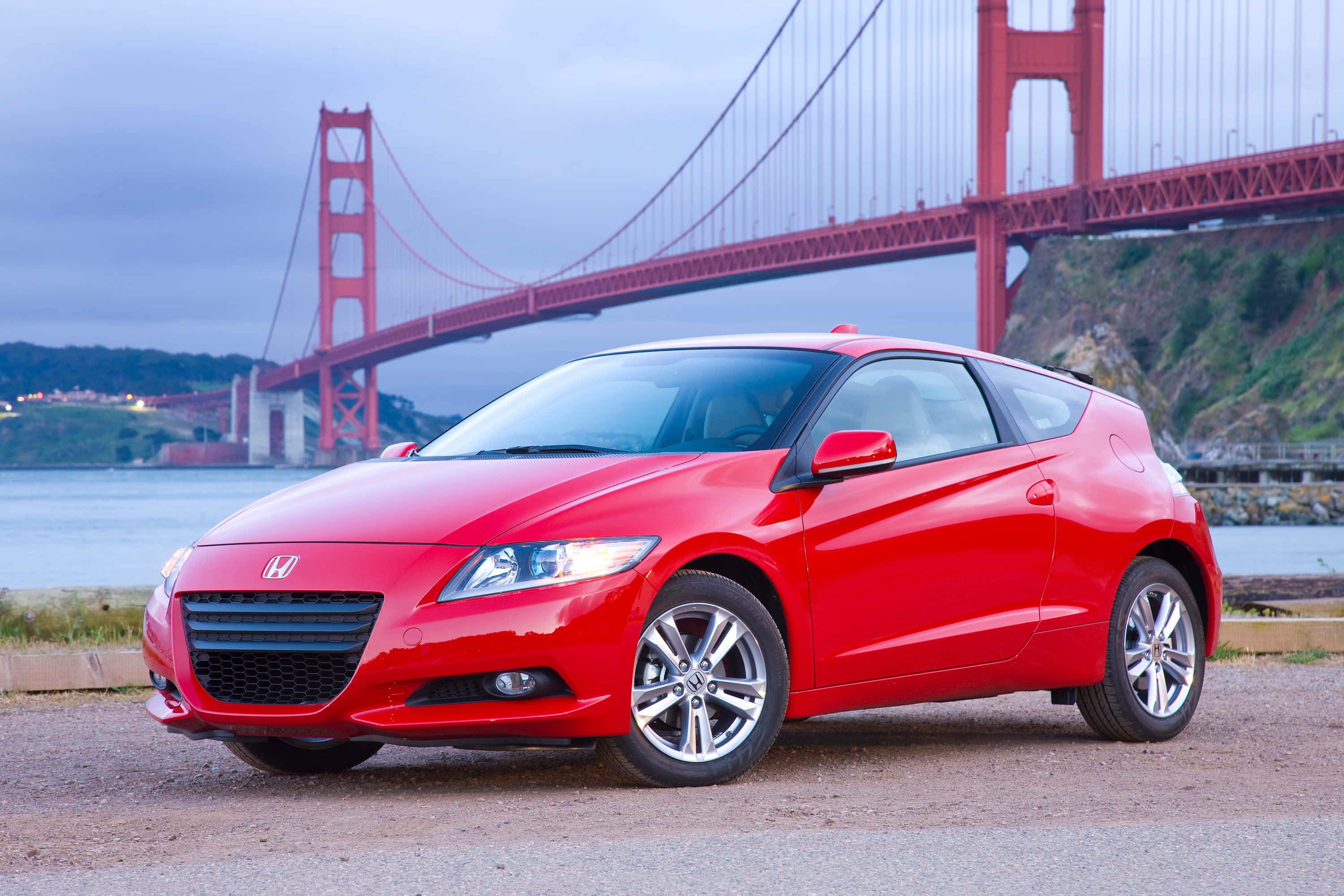 Honda Cr-z 桌布 壁紙 — 一輛鮮紅色的本田CR-Z跑車停泊在礫石岸邊，標誌性的金門大橋在迷霧背景中若隱若現。