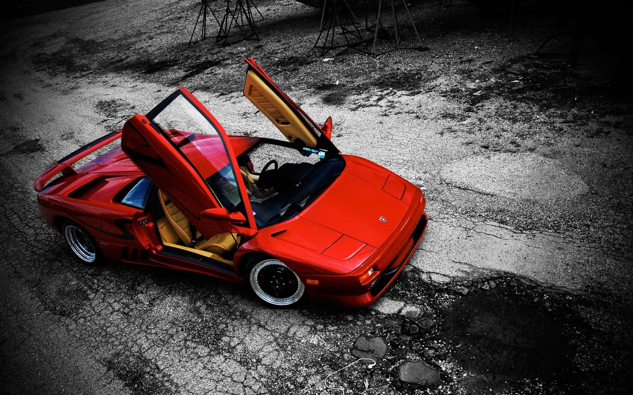 Lamborghini Diablo 桌布 壁紙 — 一輛鮮紅色的林寶堅尼 Diablo 打開鷗翼車門，戲劇性地停在高對比照明下的破裂瀝青路面上。