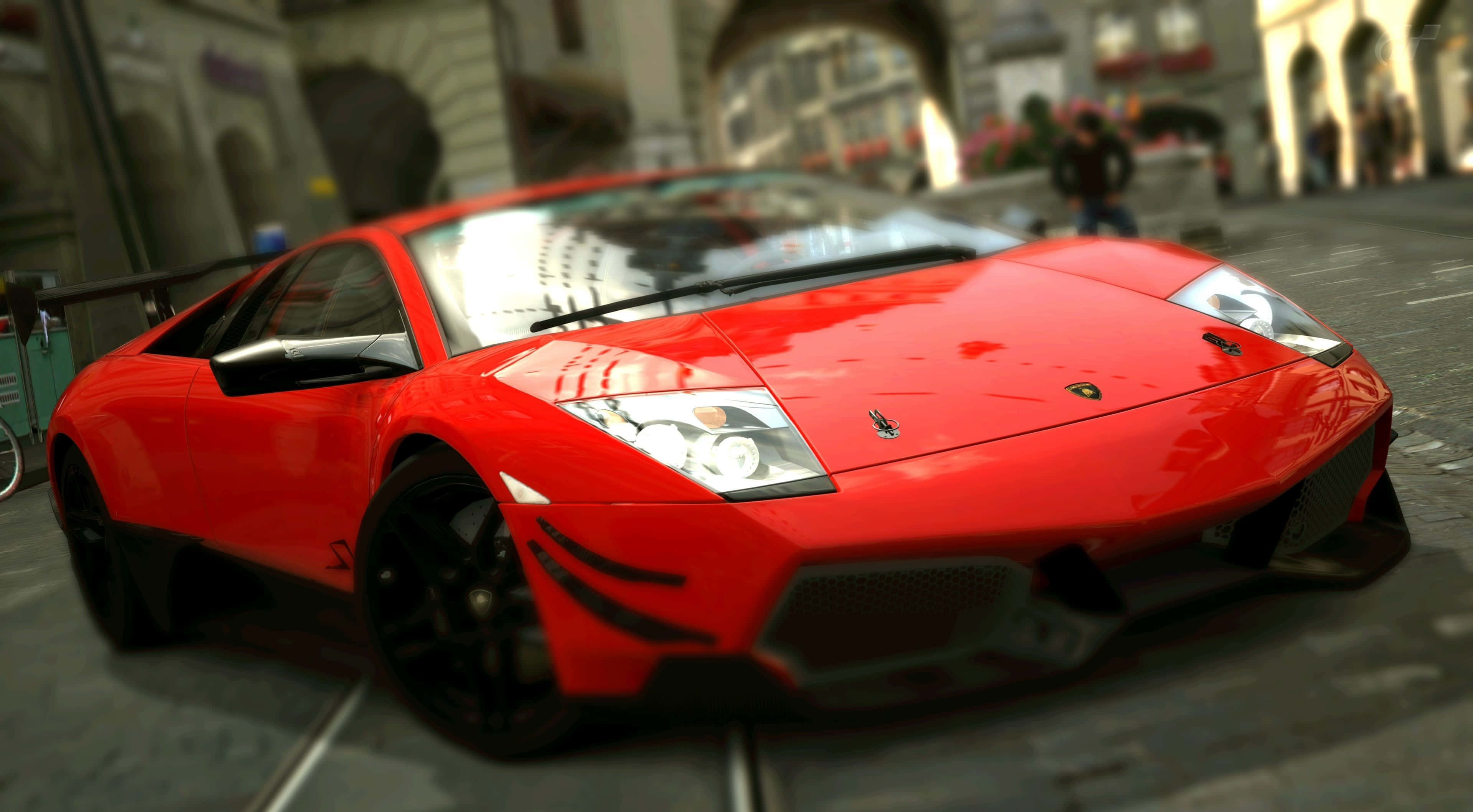 Lamborghini Murciélago 桌布 壁紙 — 一輛鮮紅色的林寶堅尼跑車在日光下閃耀，行駛在擁有歷史建築的歐洲鵝卵石街道上。