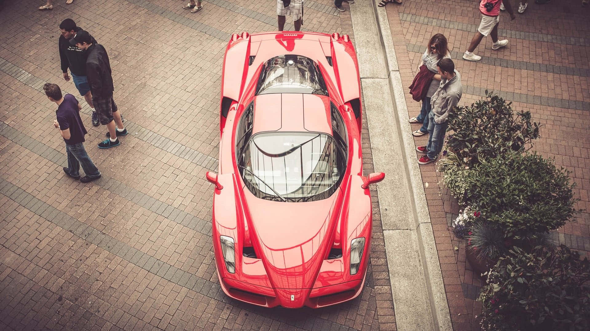 Ferrari Enzo 桌布 壁紙 — 一輛鮮紅色的法拉利 LaFerrari 停泊在磚砌廣場上，從上方吸引了大批仰慕者。