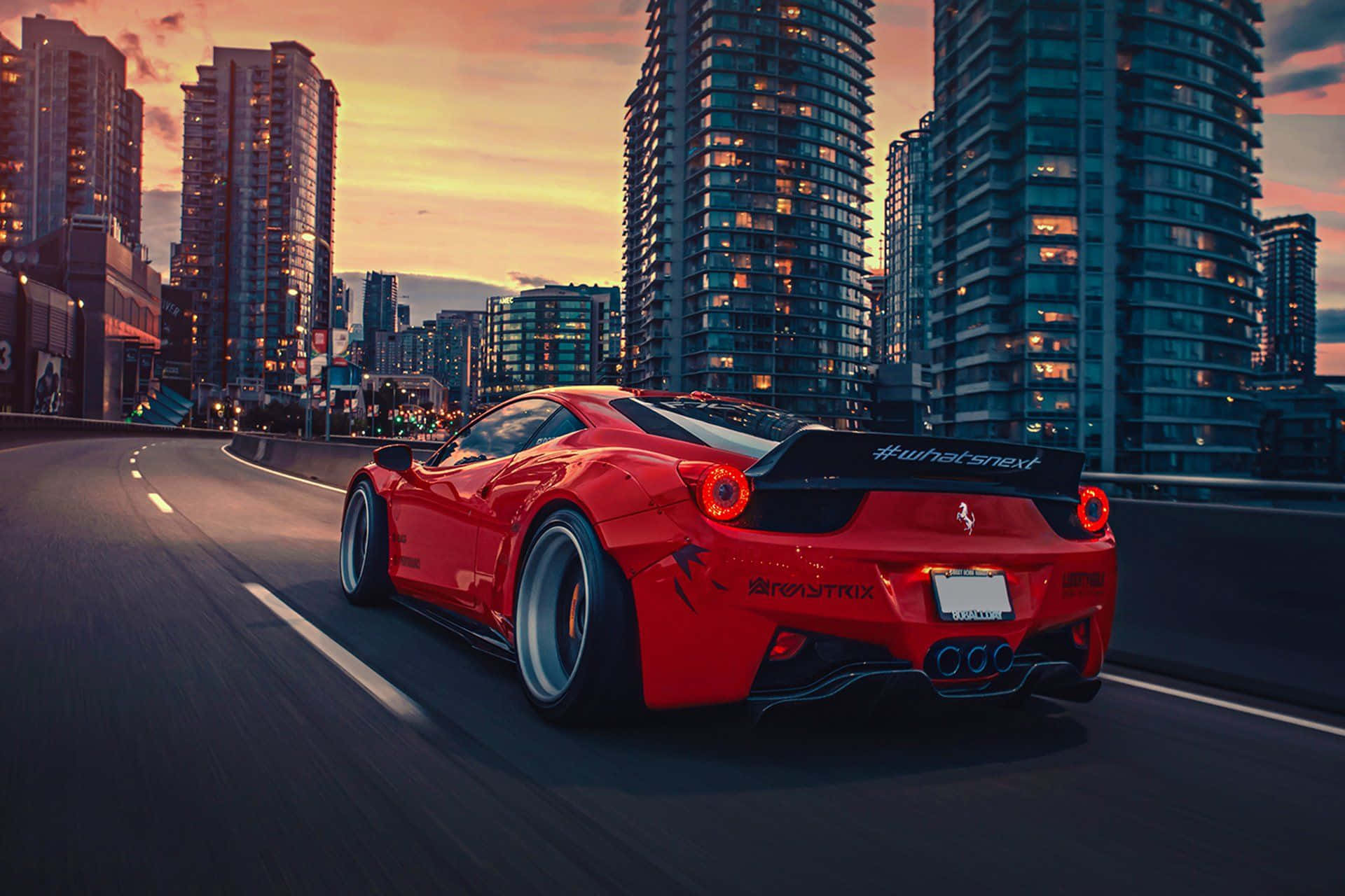 Sports Car 桌布 壁紙 — 一輛鮮紅色的法拉利在日落時分沿著城市高速公路飛馳，背後聳立的摩天大樓閃閃發光。