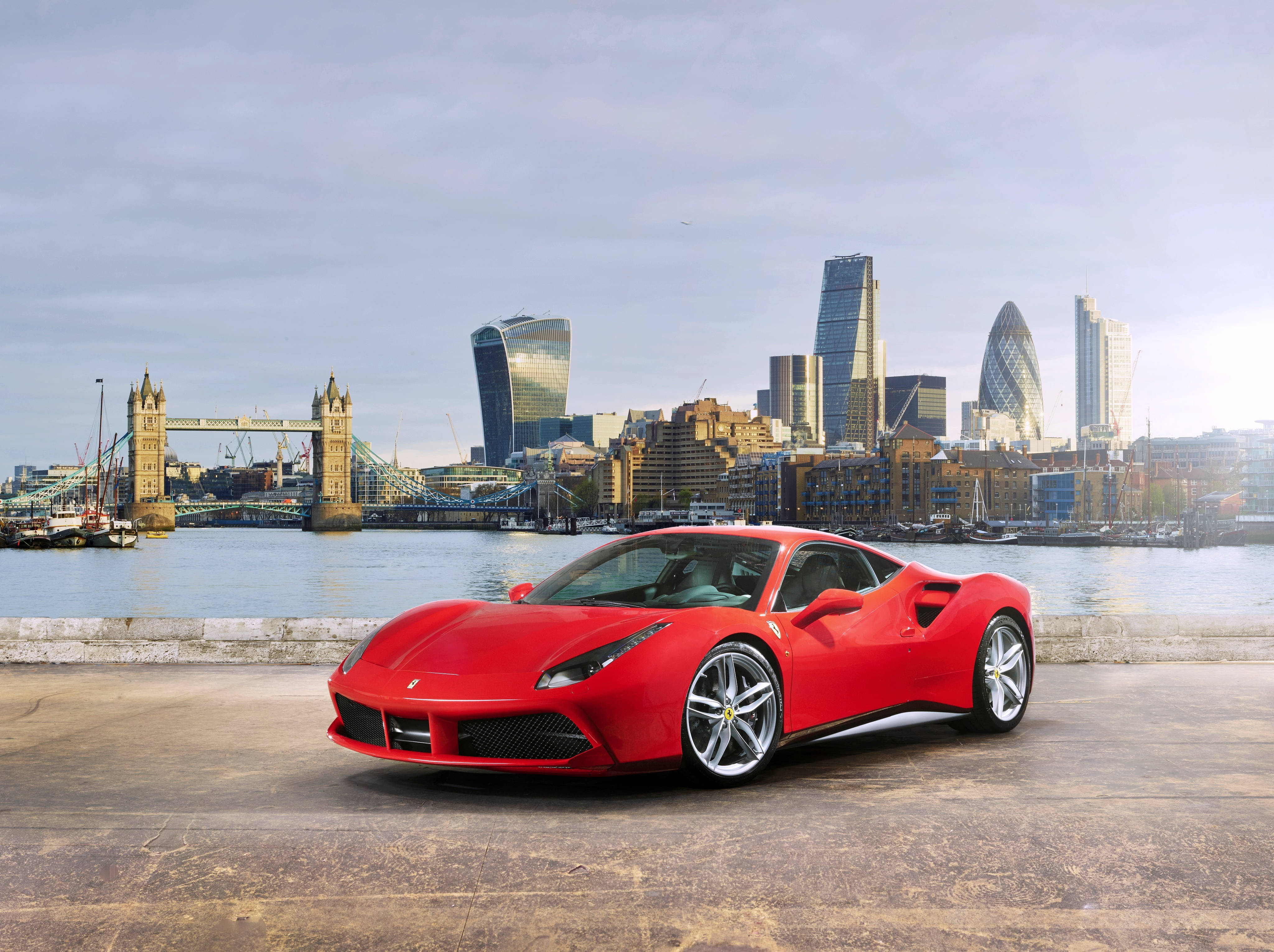 Sports Car 桌布 壁紙 — 一輛鮮紅色的法拉利跑車停泊在河畔碼頭，背景是倫敦標誌性的天際線和塔橋。
