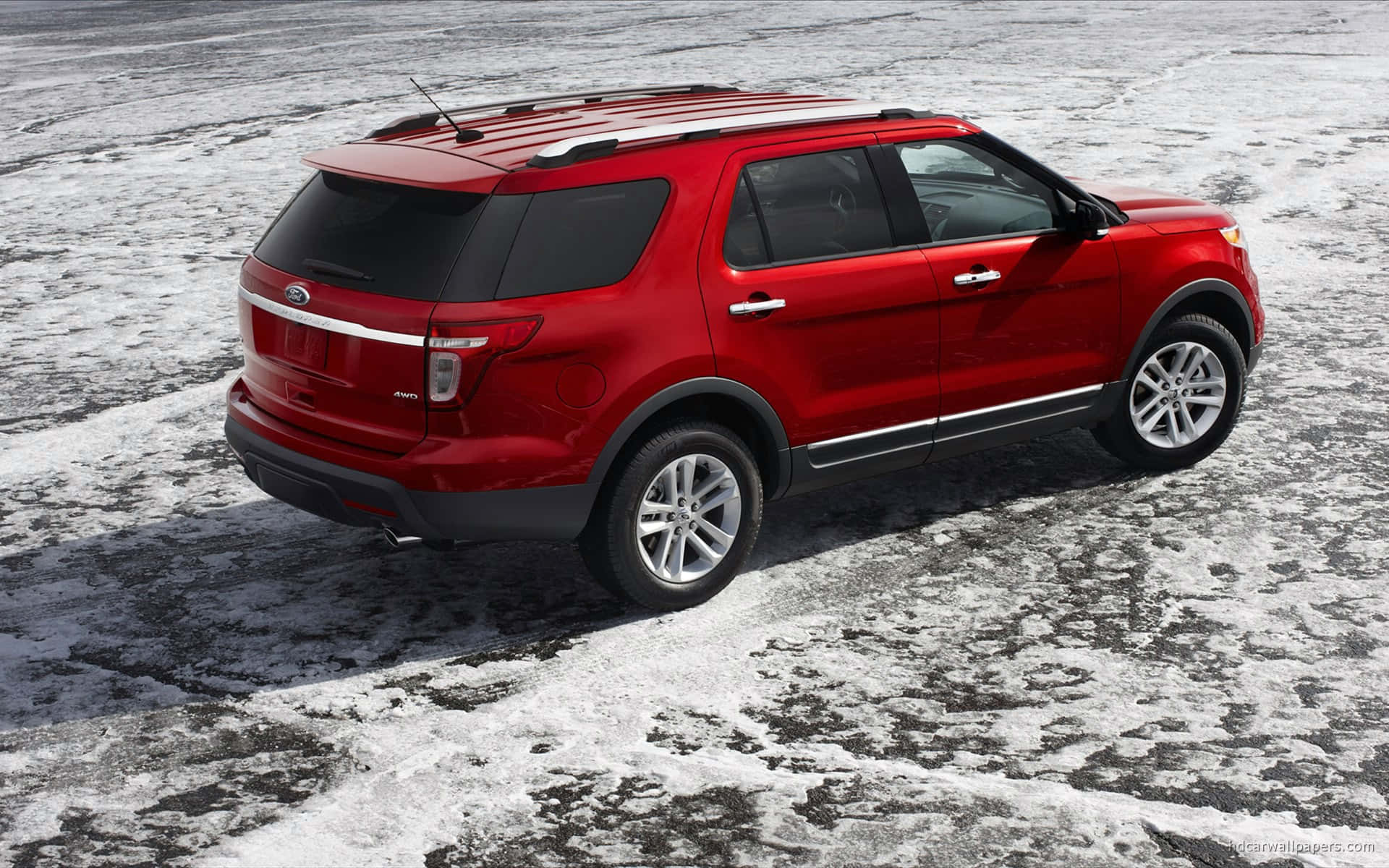 Ford Explorer 桌布 壁紙 — 一輛鮮紅色的福特探險者SUV在明亮的日光下，停在有紋理的雪地上。