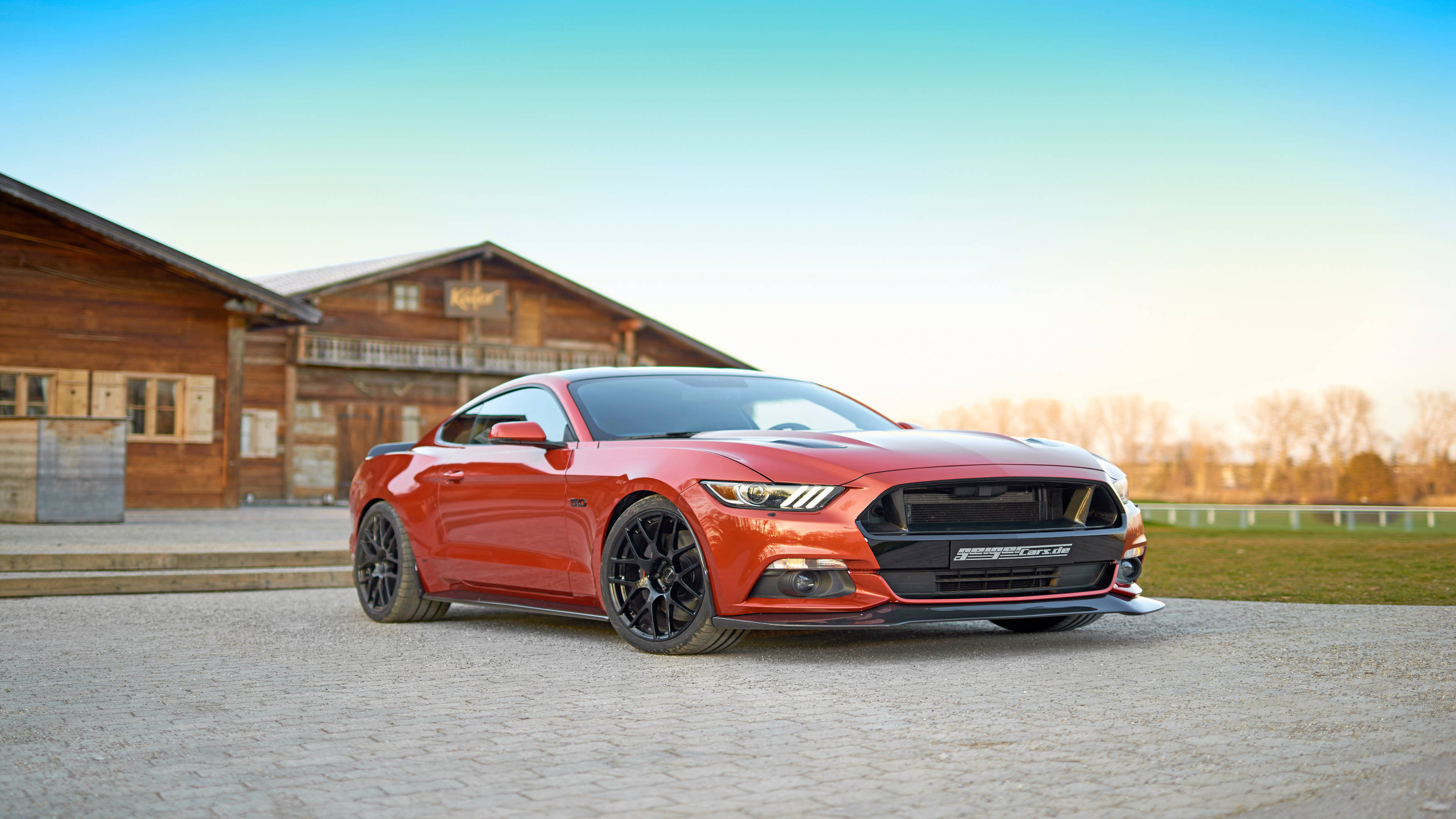 mustang HD 桌布 壁紙 — 一輛鮮紅色的福特野馬跑車停在碎石車道上，前面是質樸的木製穀倉，正值黃金時刻。