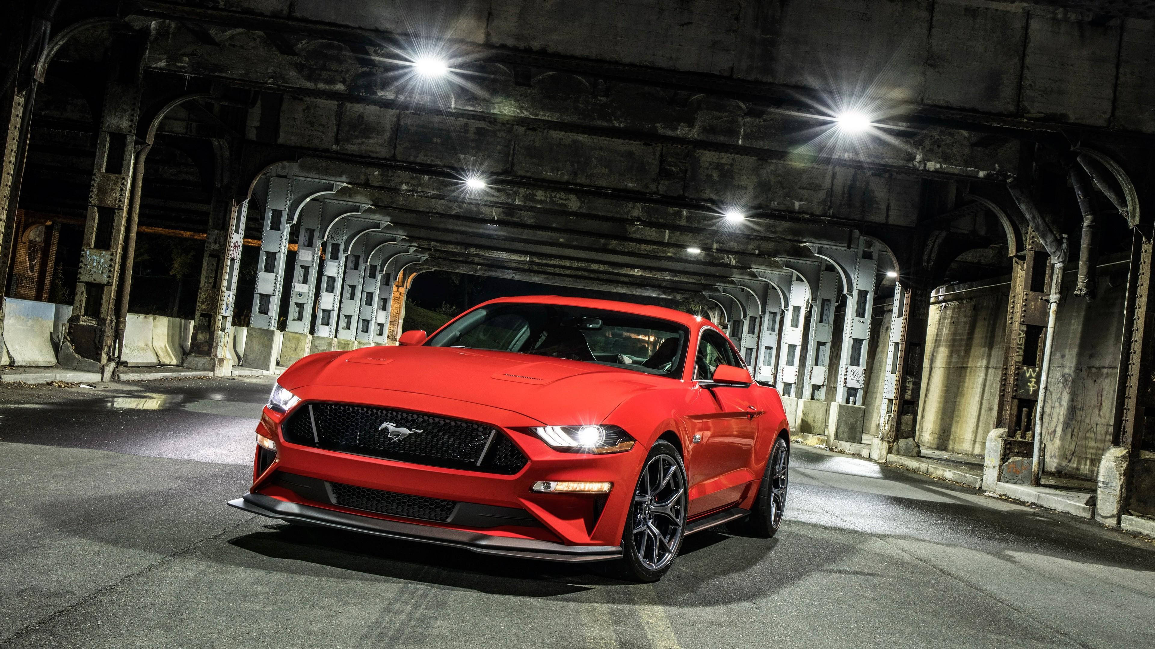 mustang HD 桌布 壁紙 — 一輛鮮紅色的福特野馬跑車在風化的混凝土隧道內，在明亮的聚光燈下閃閃發光。