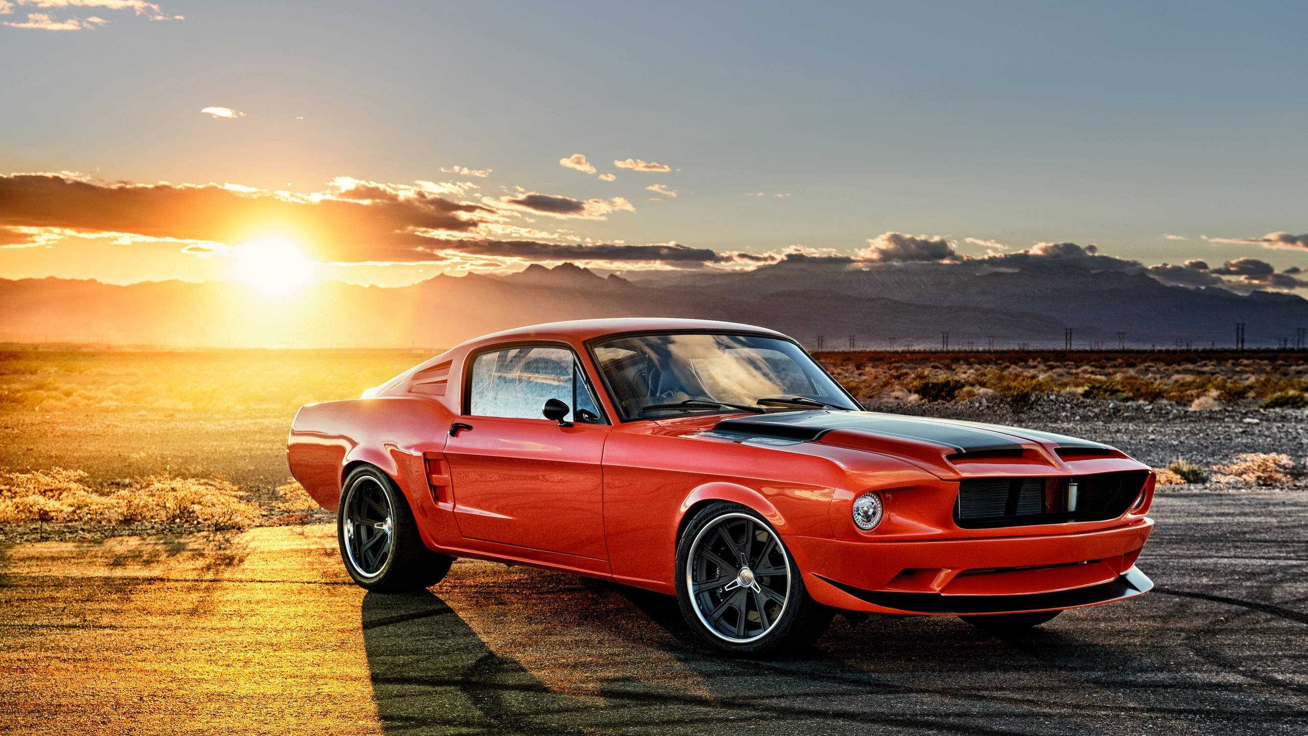 Muscle Car 桌布 壁紙 — 一輛鮮紅色的經典肌肉車在日落時分停泊在瀝青路上，背景是山脈。