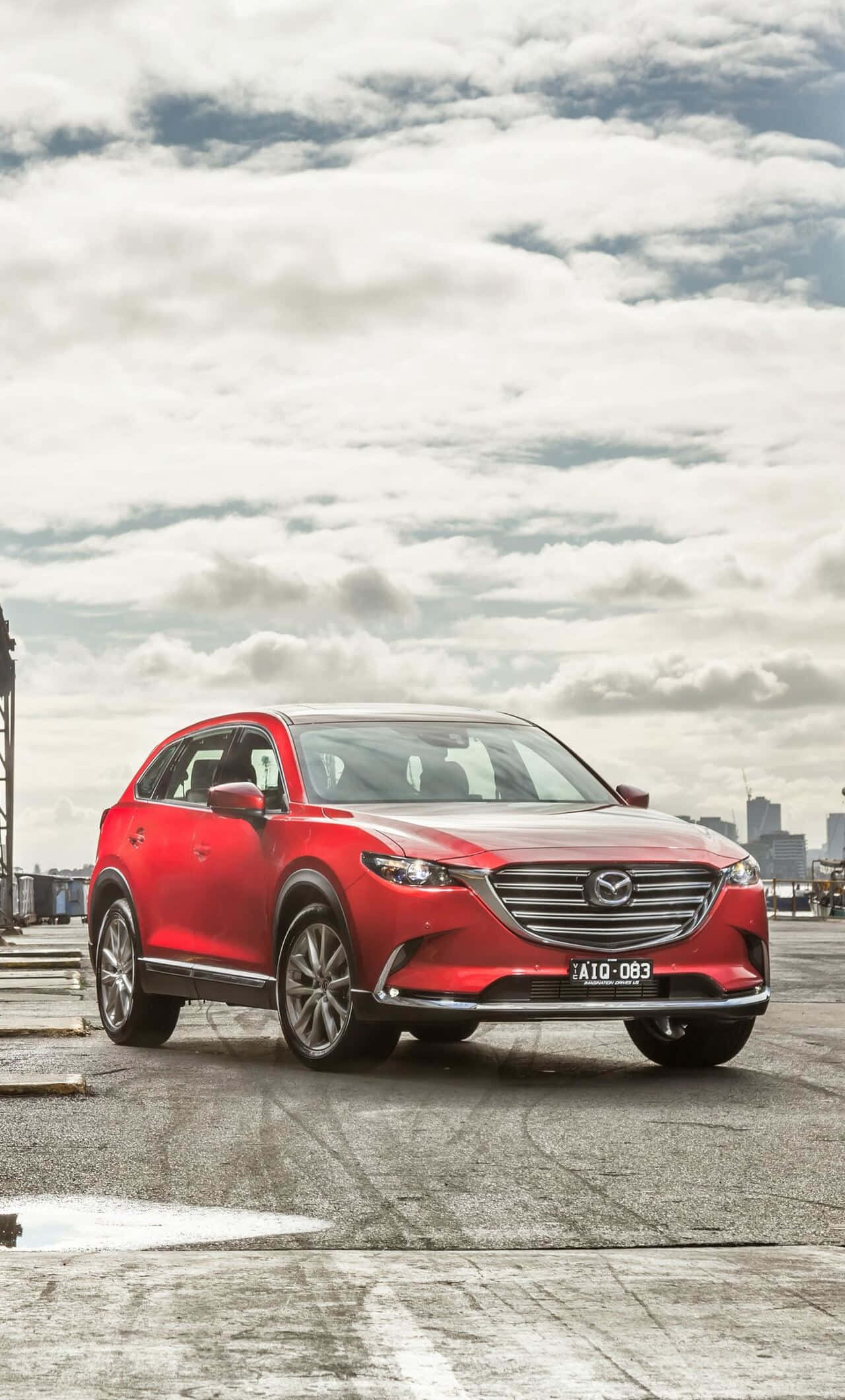 Mazda Cx-9 桌布 壁紙 — 一輛鮮紅色的萬事得CX-5 SUV停在濕漉漉的屋頂上，背後是陰天和遠處的城市天際線。