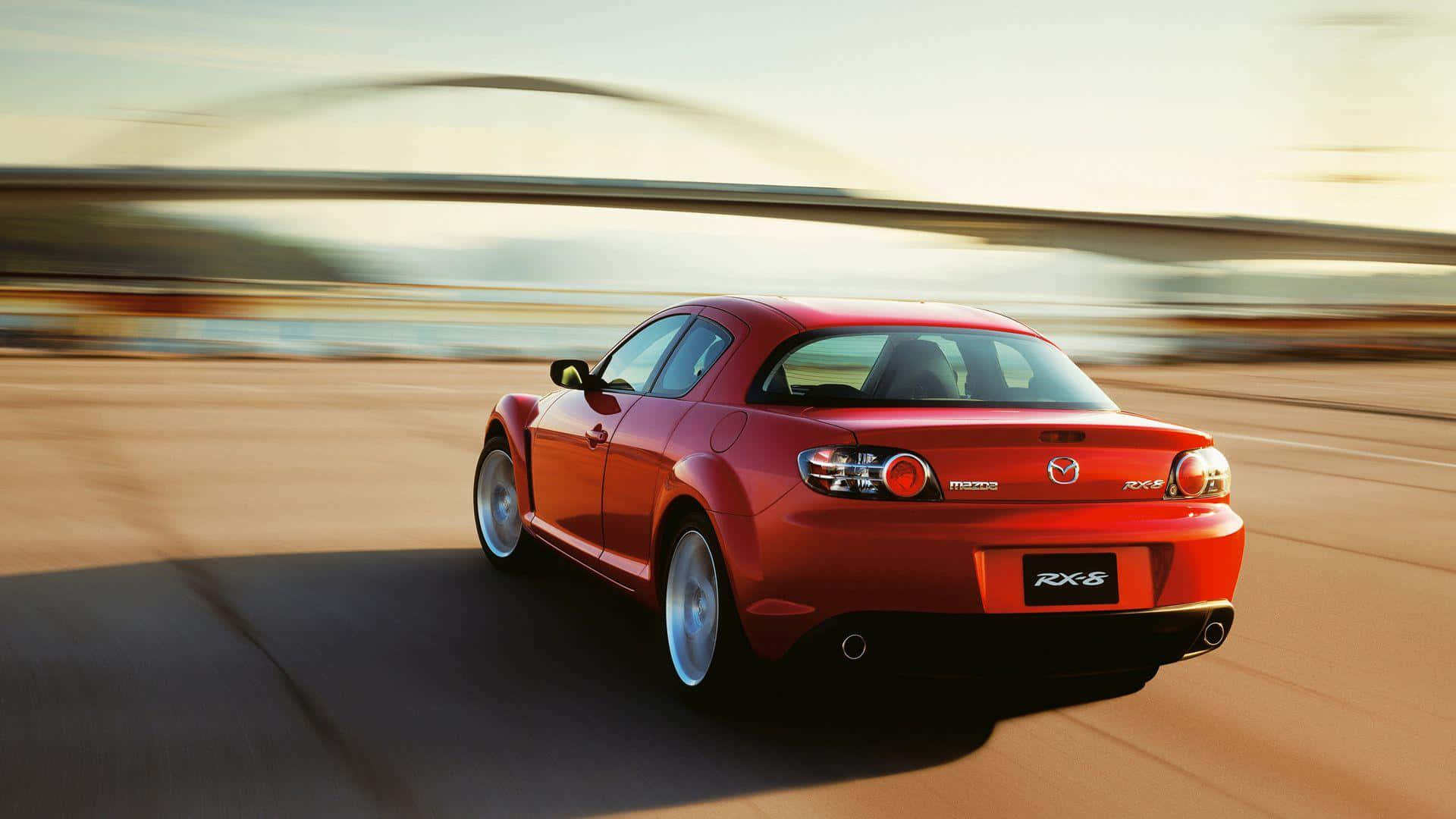Mazda Rx-8 桌布 壁紙 — 一輛鮮紅色的萬事得RX-8跑車在陽光明媚的高速公路上疾馳，背景因動態模糊而呈現條紋效果。