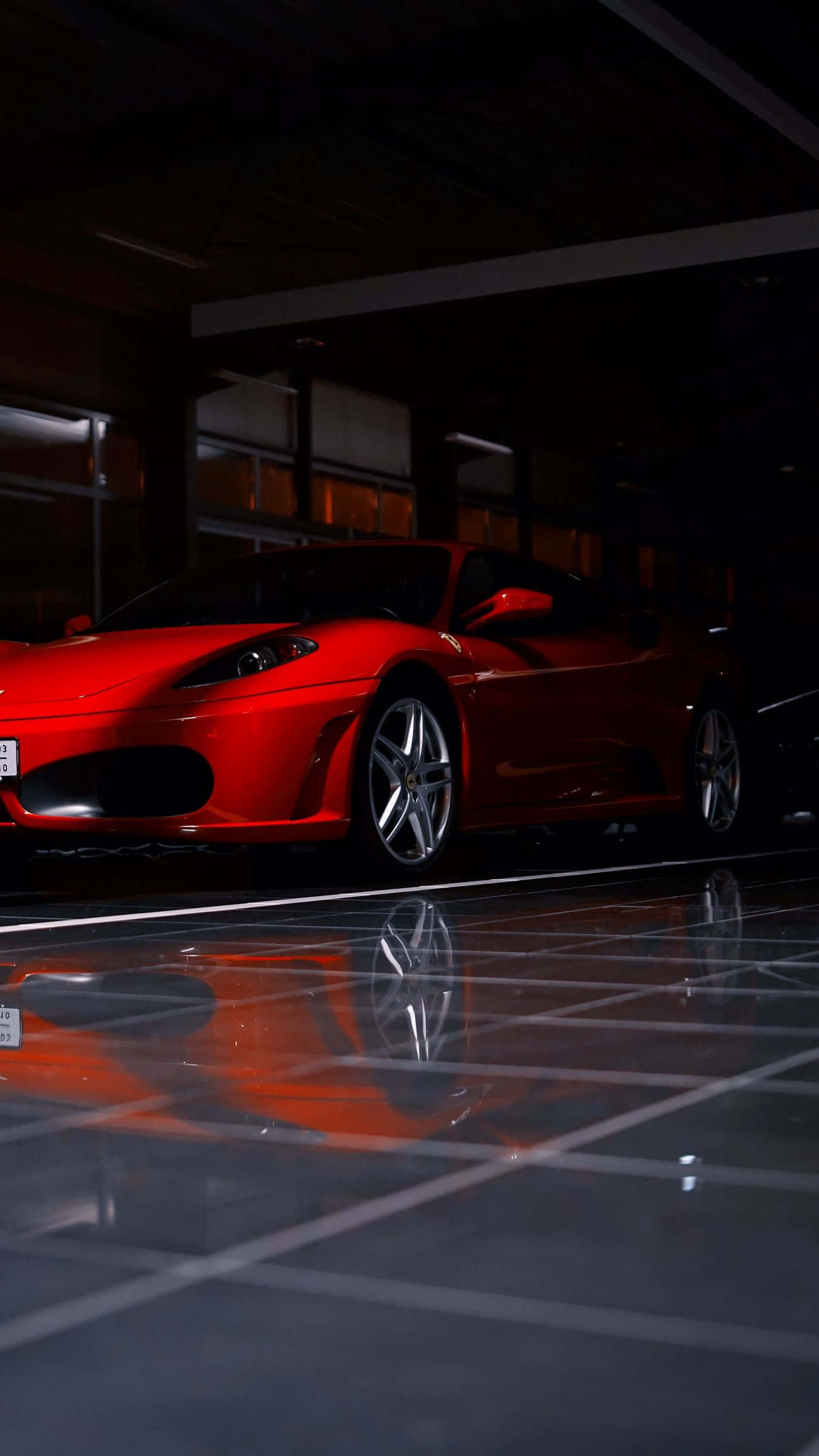 Ferrari F430 桌布 壁紙 — 一輛鮮紅色的跑車在戲劇性的燈光下，在一個舖有反光瓷磚地板的時尚現代車庫中閃閃發光。