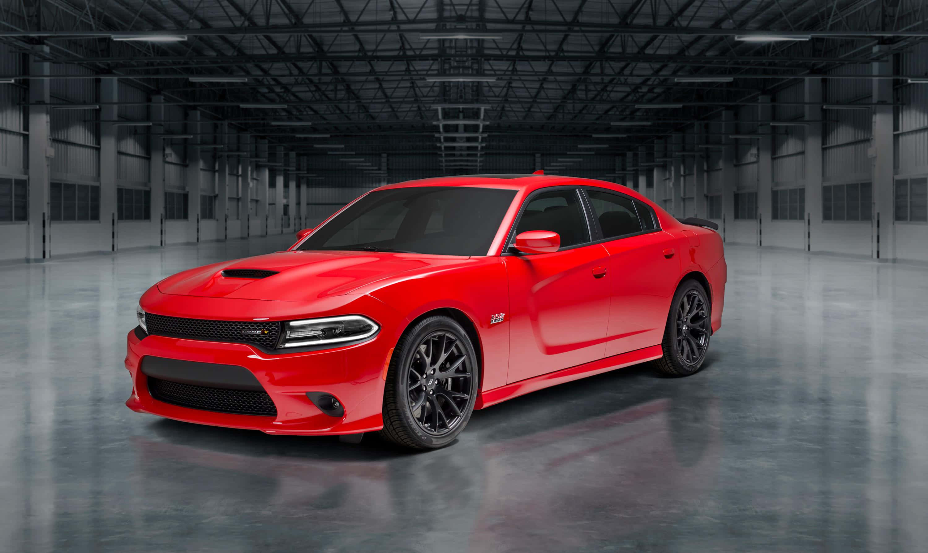 Dodge Charger 桌布 壁紙 — 一輛鮮紅色的道奇 Charger SRT Hellcat 在寬敞的工業倉庫中，於高樓底和混凝土地板上的攝影棚燈光下閃閃發光。