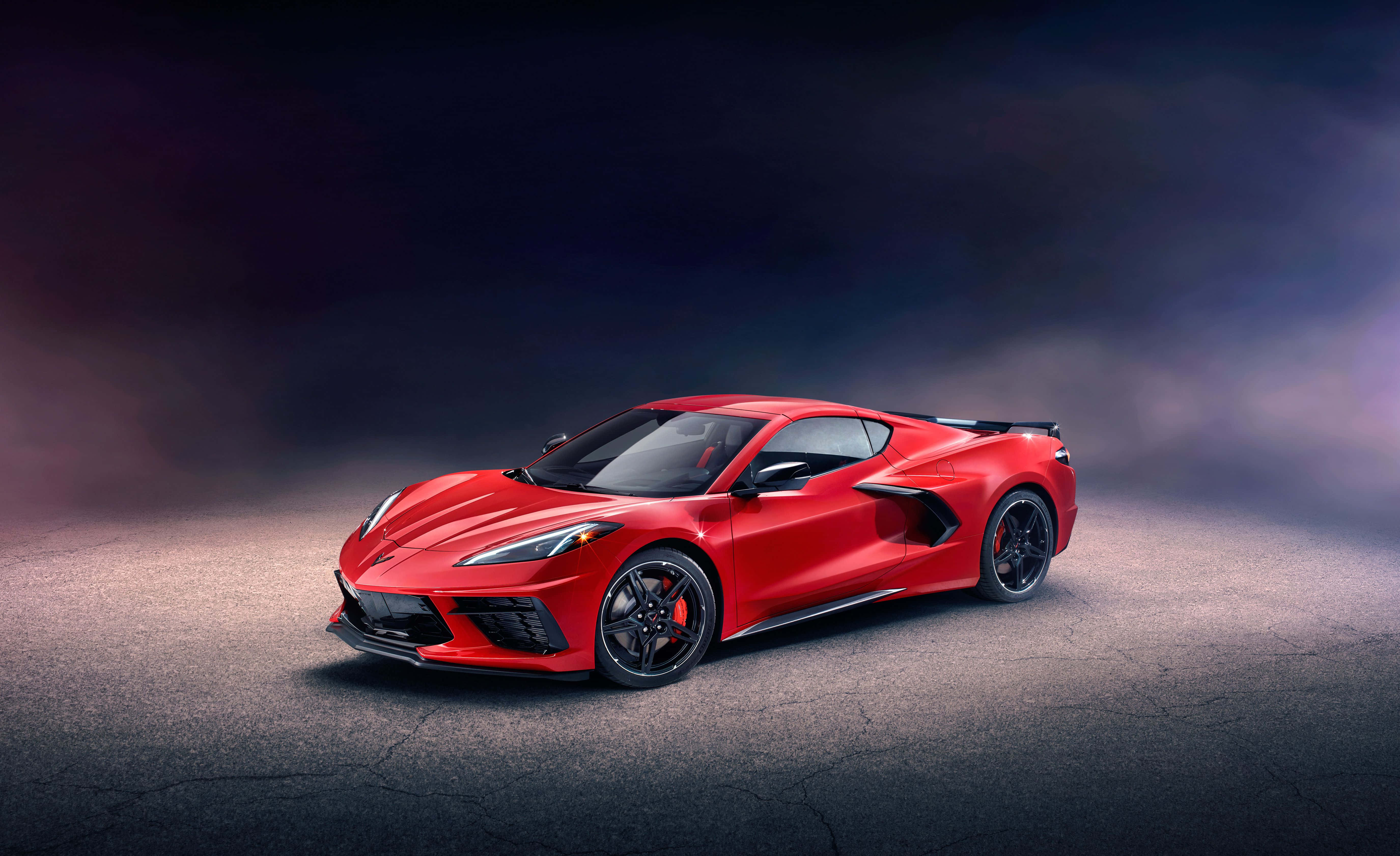 Chevrolet Corvette Stingray 桌布 壁紙 — 一輛鮮紅色跑車在戲劇性的工作室燈光下，在煙霧瀰漫的黑暗背景中閃閃發光。