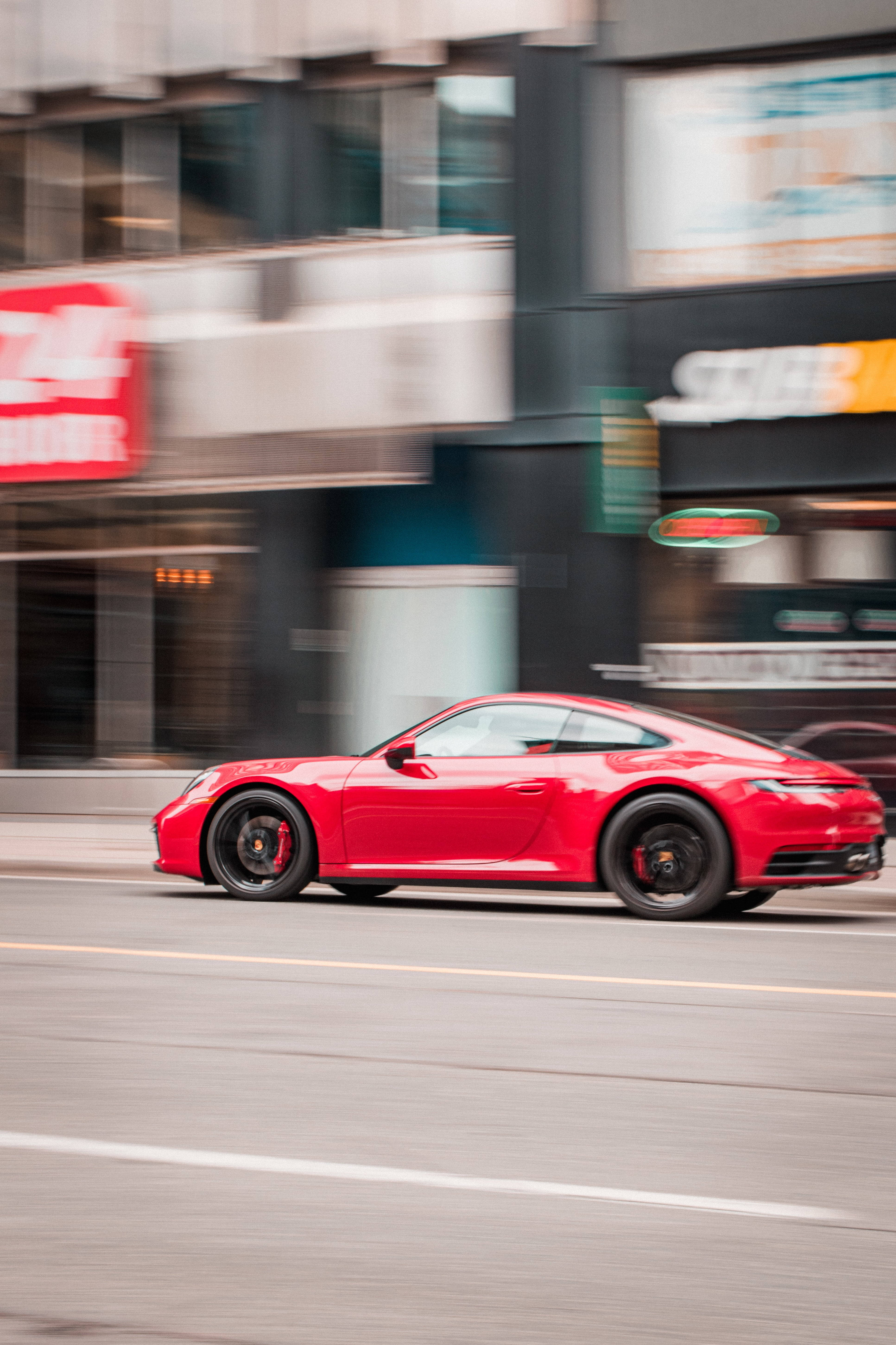 speeding car 桌布 壁紙 — 一輛鮮紅色跑車在都市背景的動態模糊中沿著城市街道飛馳。
