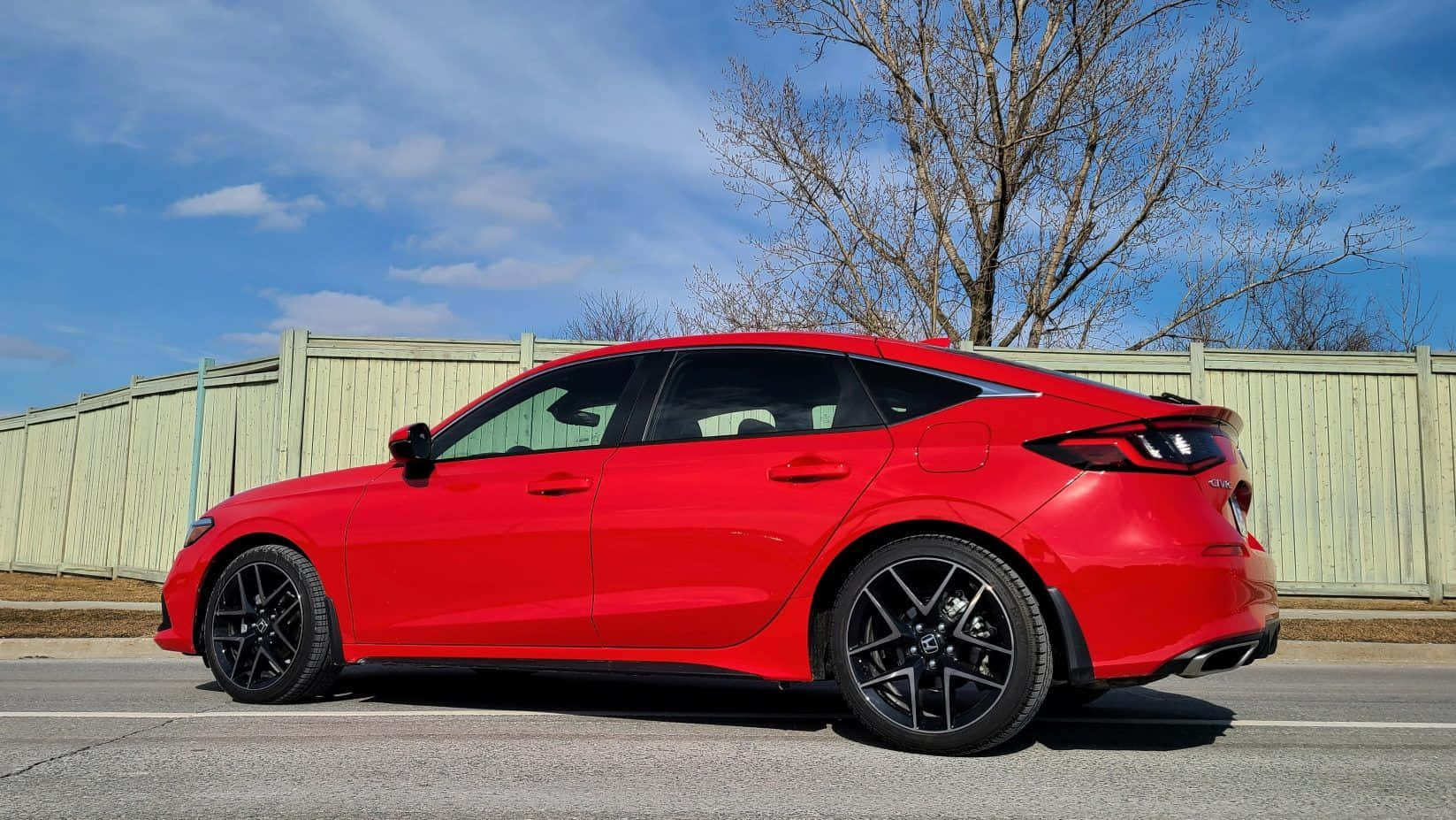 Honda Civic 桌布 壁紙 — 一輛鮮紅色跑車配黑色輪圈，停在瀝青路上，背景是晴朗藍天和光禿禿的樹木。