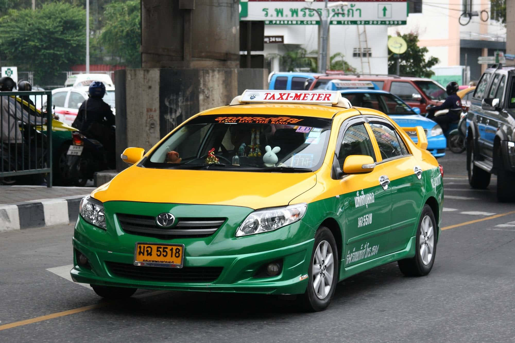 taxi 桌布 壁紙 — 一輛鮮綠色和黃色的的士在曼谷繁忙的街道上行駛，背景有其他車輛和電單車。
