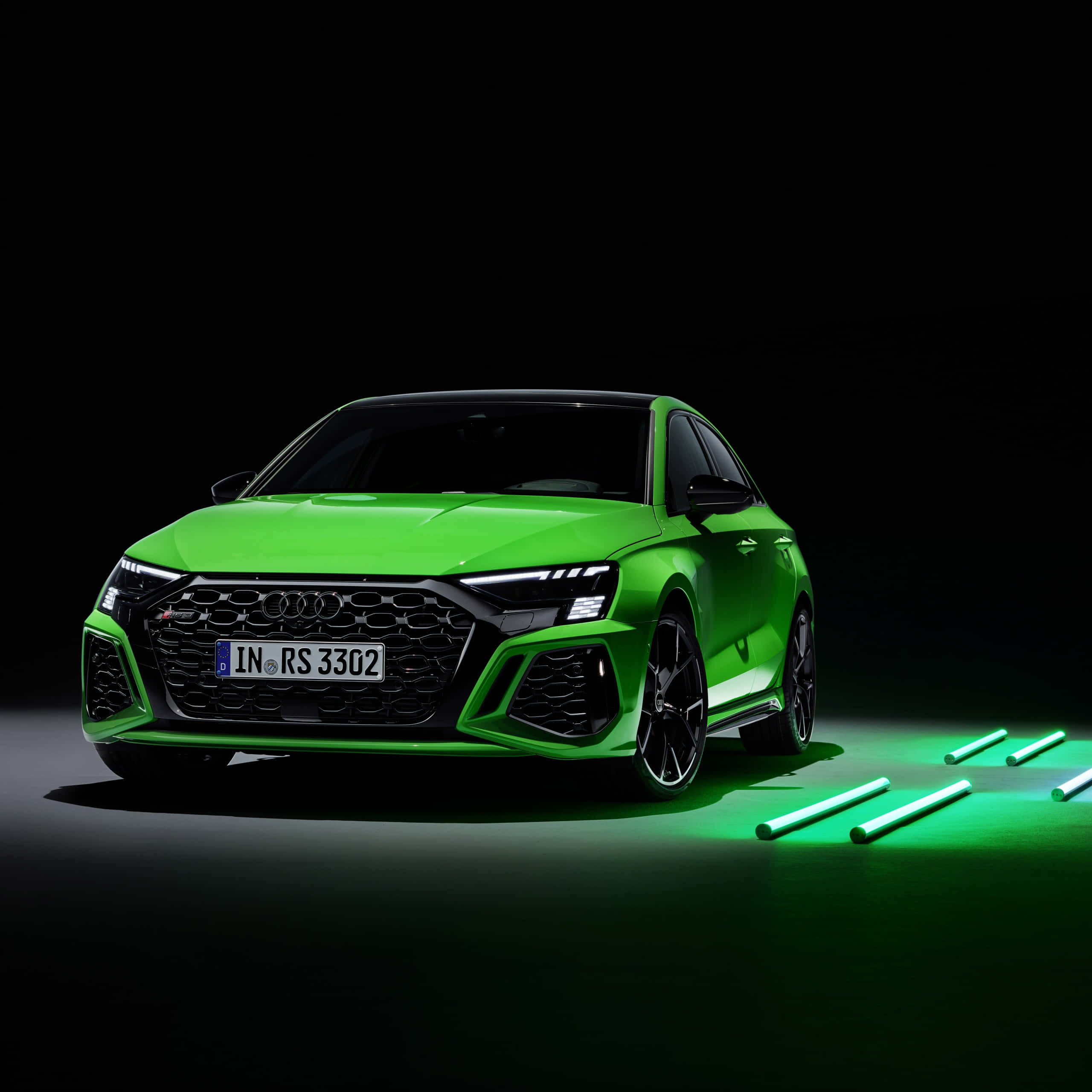 奧迪 桌布 壁紙 — 一輛鮮綠色嘅Audi RS3 Sportback喺黑色背景同發光綠色管嘅地板上面，喺攝影棚燈光下閃閃發光。