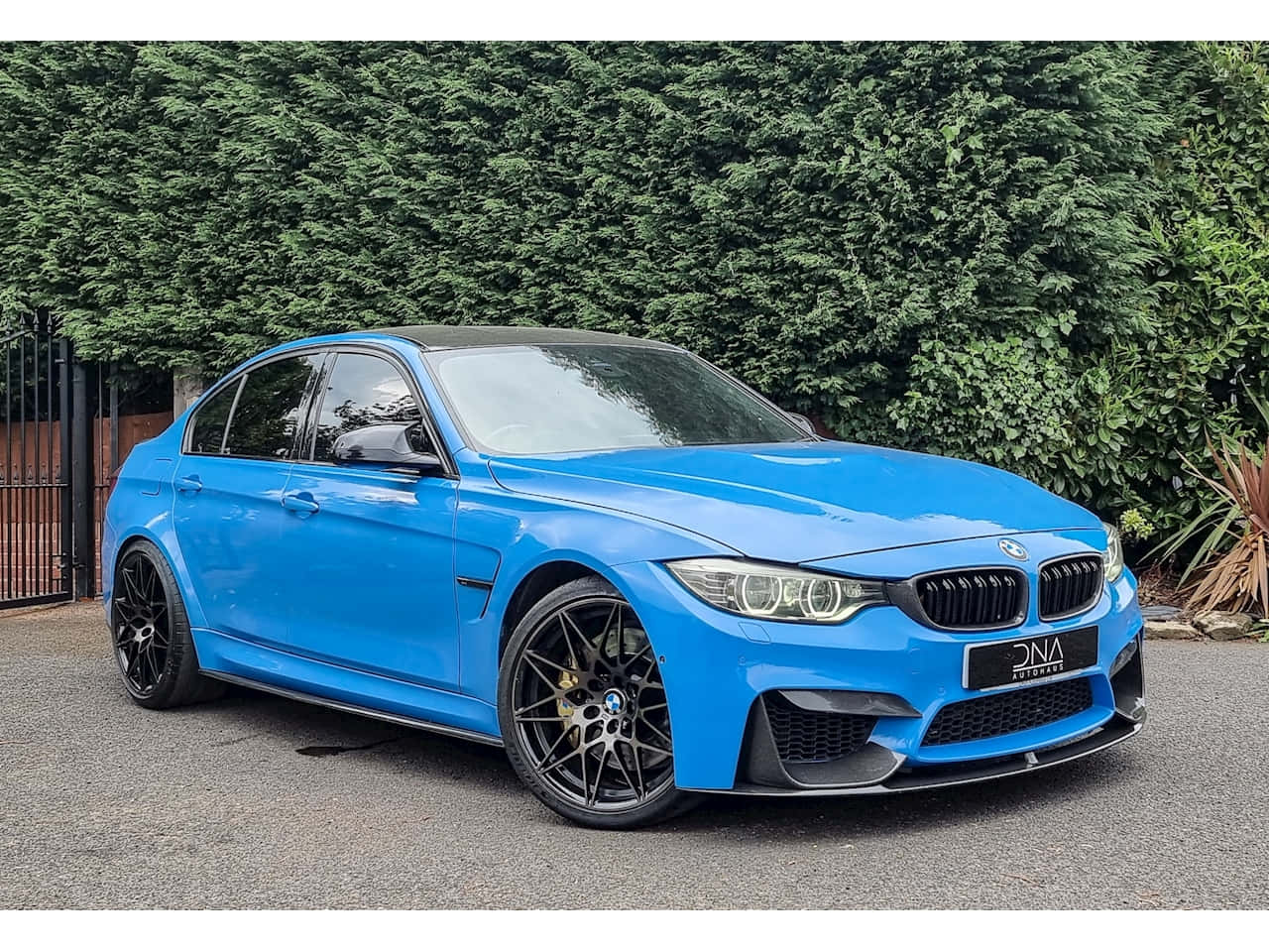 Bmw 3 Series 桌布 壁紙 — 一輛鮮藍色BMW M3房車配黑色輪圈，停在碎石路上，前面是茂密的綠色樹籬。