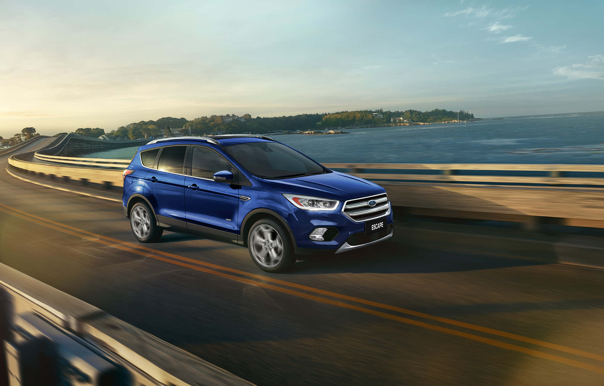 Ford Escape 桌布 壁紙 — 一輛鮮藍色的福特 Escape SUV 在黃金時段沿著海岸公路行駛，以模糊的動態襯托寧靜的海洋背景。