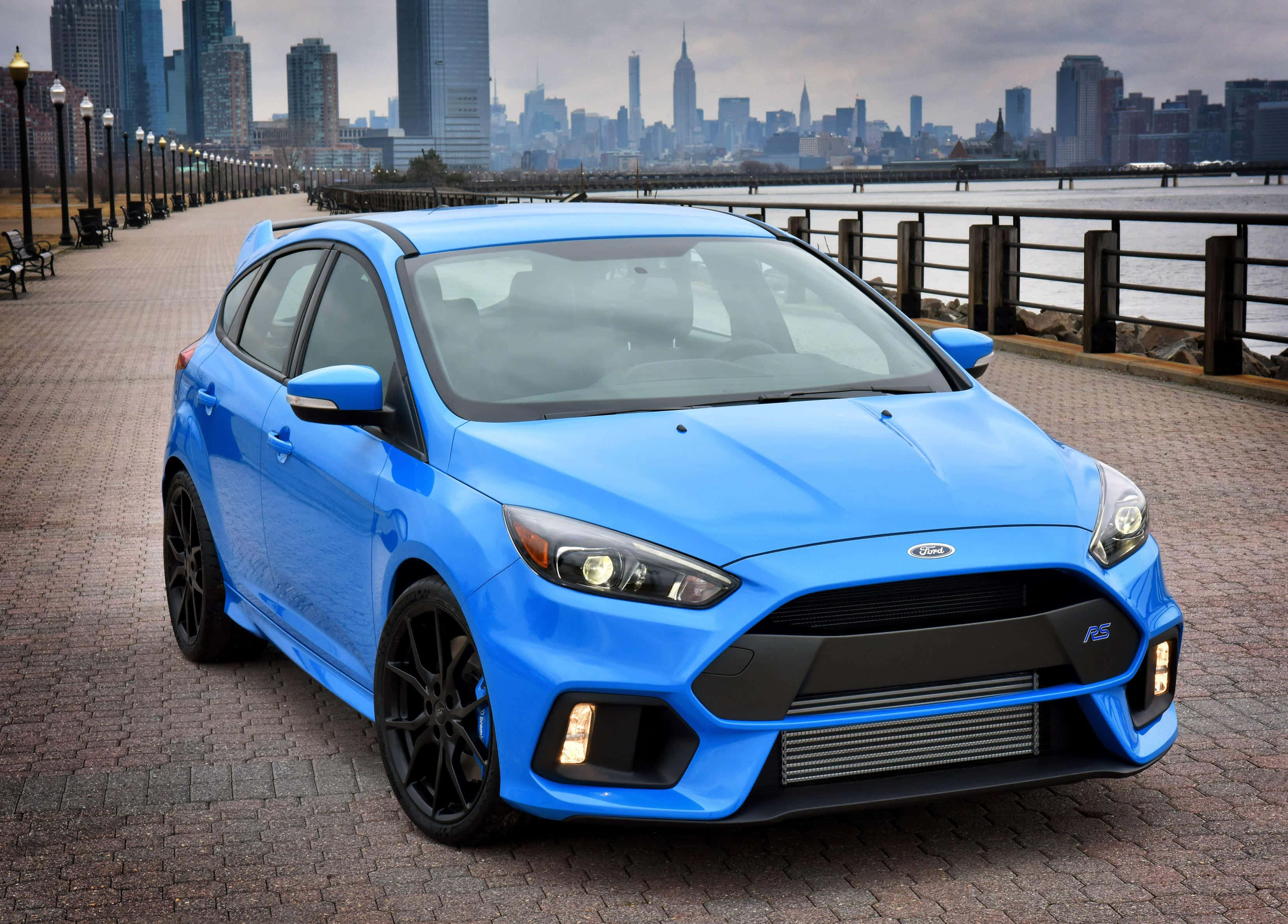 Ford Focus 桌布 壁紙 — 一輛鮮藍色的福特福克斯RS停在磚砌長廊上，背景是城市天際線。