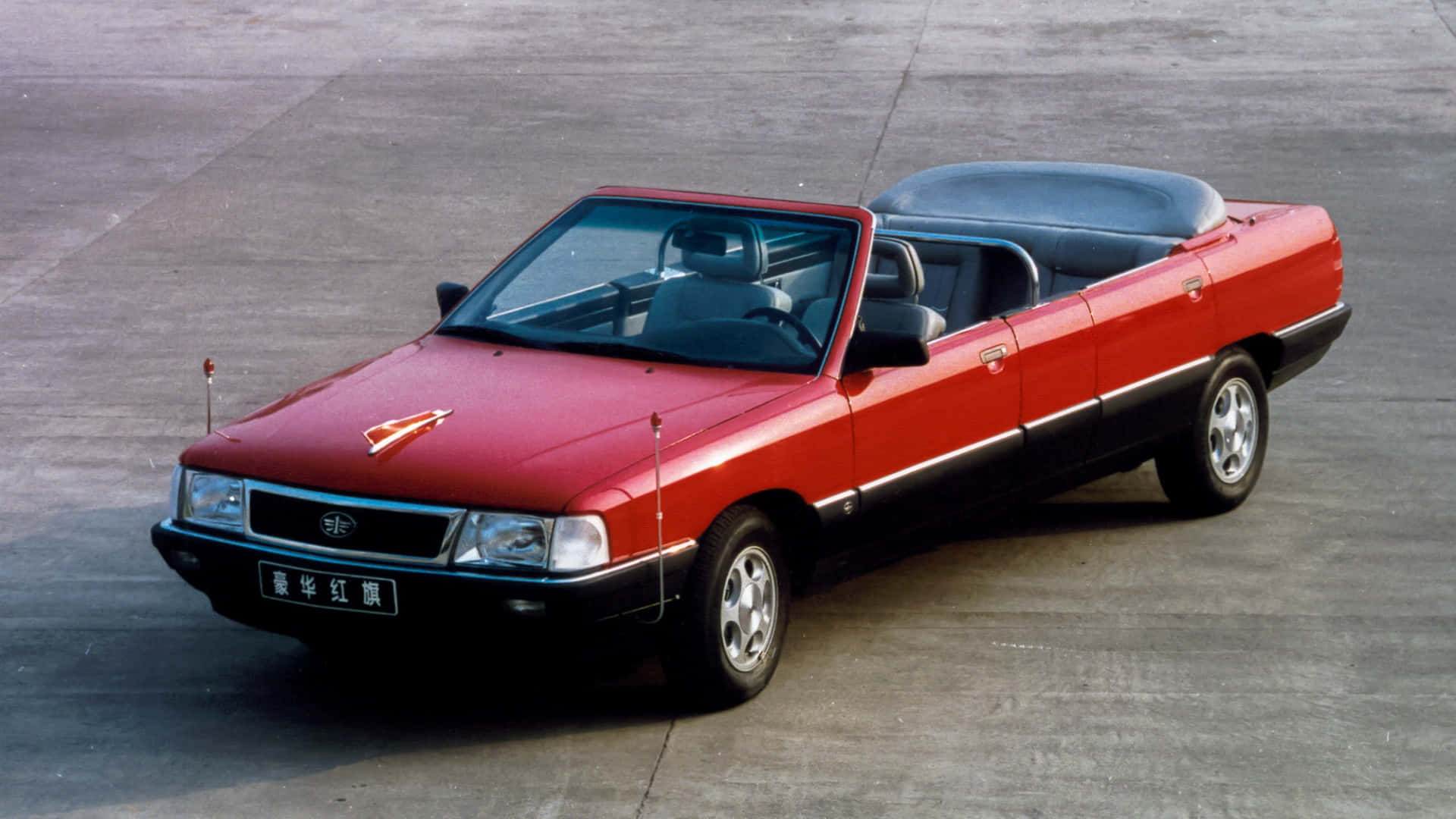 Hongqi 桌布 壁紙 — 一輛鮮豔的紅色和黑色敞篷車，帶有折疊軟頂，停在灰色混凝土表面上。