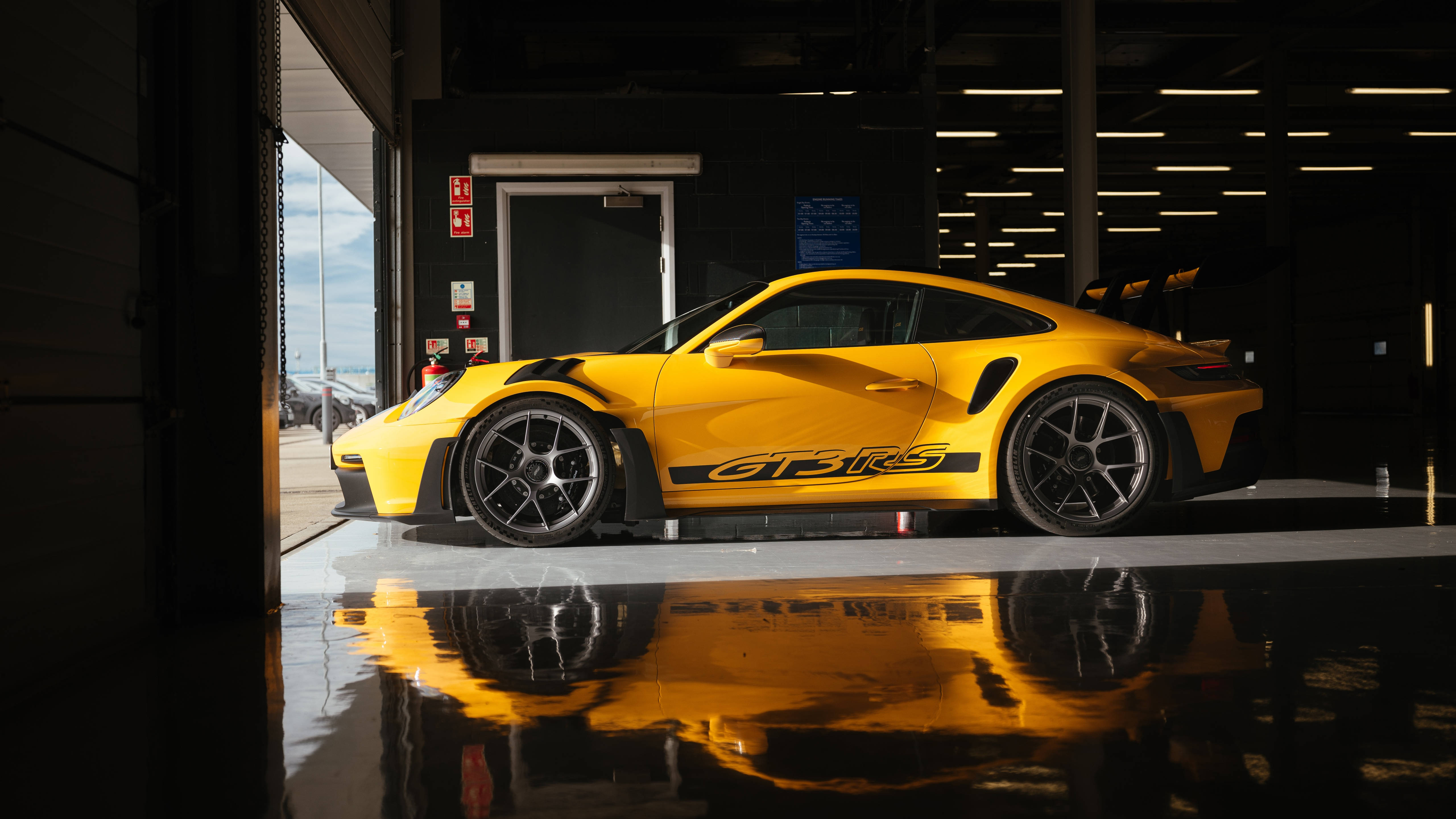 保時捷 桌布 壁紙 — 一輛鮮黃色的保時捷911 GT3 RS在車庫燈光下閃耀，在濕漉漉的混凝土地板上留下完美倒影。