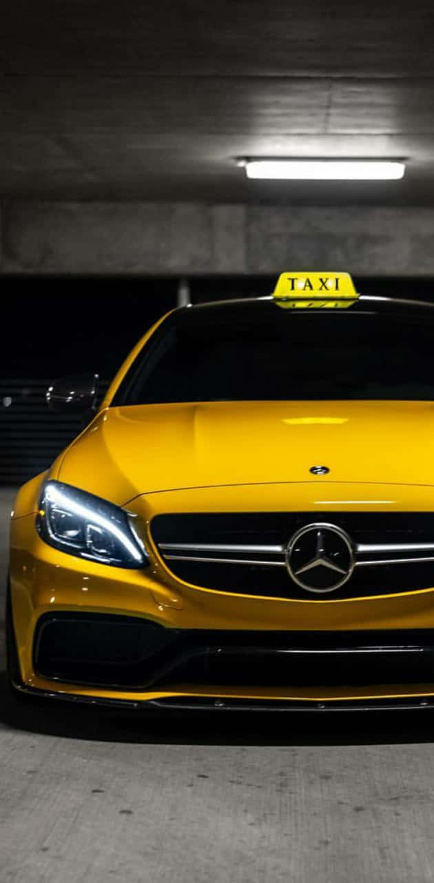 Yellow Cab 桌布 壁紙 — 一輛鮮黃色的平治的士在昏暗的混凝土停車場中，在螢光燈下閃閃發光。