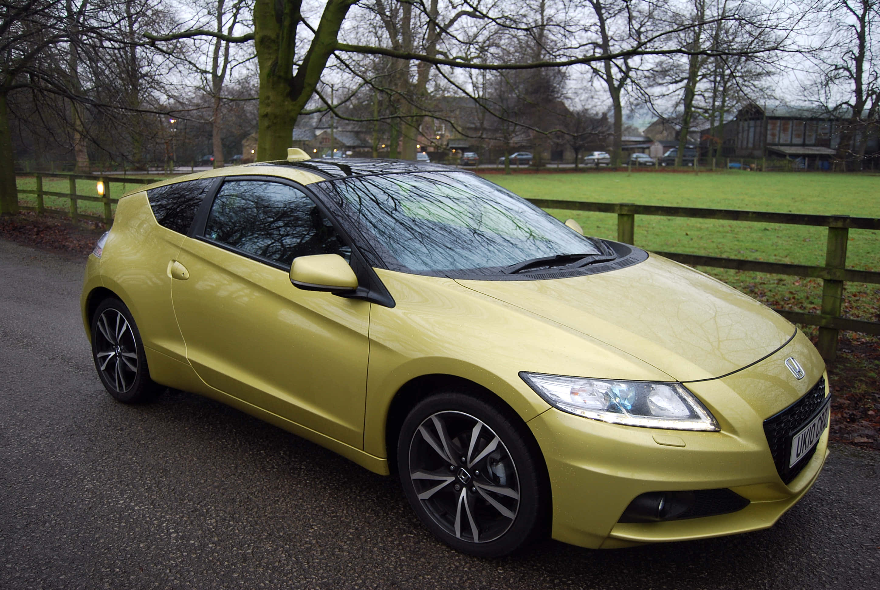 Honda Cr-z 桌布 壁紙 — 一輛鮮黃色的本田 CR-Z 跑車停泊在碎石路上，旁邊有木柵欄和無葉的樹木，環境鄉村。