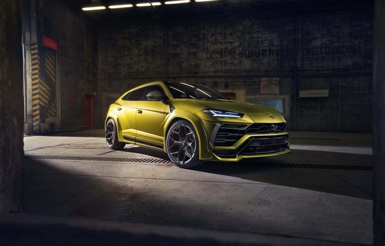 Lamborghini Urus 桌布 壁紙 — 一輛鮮黃色的林寶堅尼 Urus SUV 在光線強烈的工業車庫內閃閃發光。