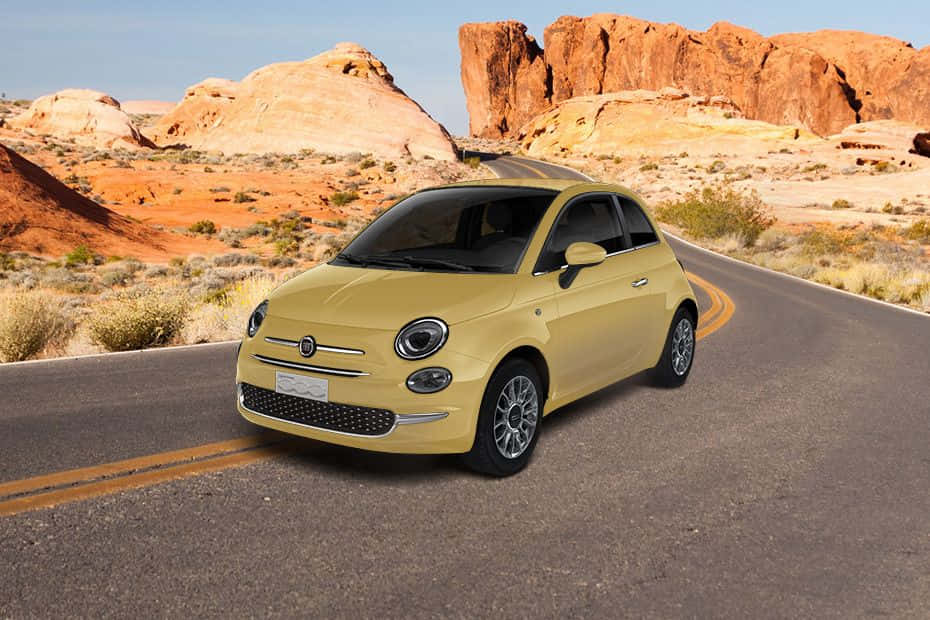 Fiat 500 桌布 壁紙 — 一輛黃色Fiat 500在晴朗藍天下沿著蜿蜒的沙漠公路行駛，兩旁是高聳的紅色岩層。