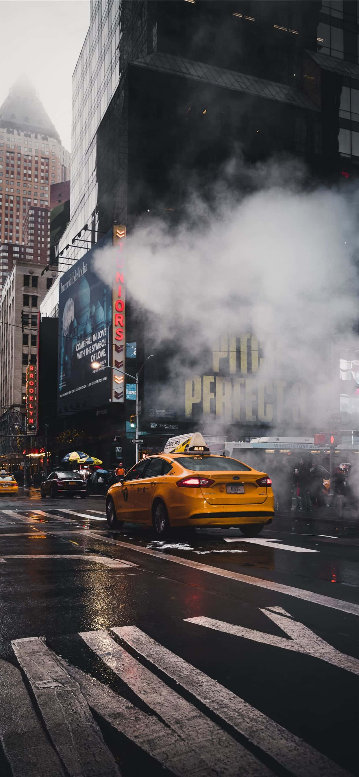 Yellow Cab 桌布 壁紙 — 一輛黃色的士在濕滑的紐約街道上行駛，附近高聳的廣告牌旁，地鐵通風口冒出濃濃蒸氣。