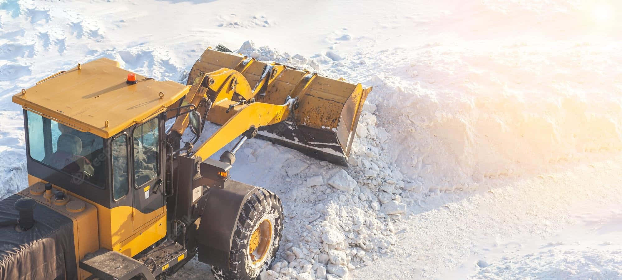 Snowplow 桌布 壁紙 — 一輛黃色除雪推土機在明亮的冬日陽光下推動一大堆雪。