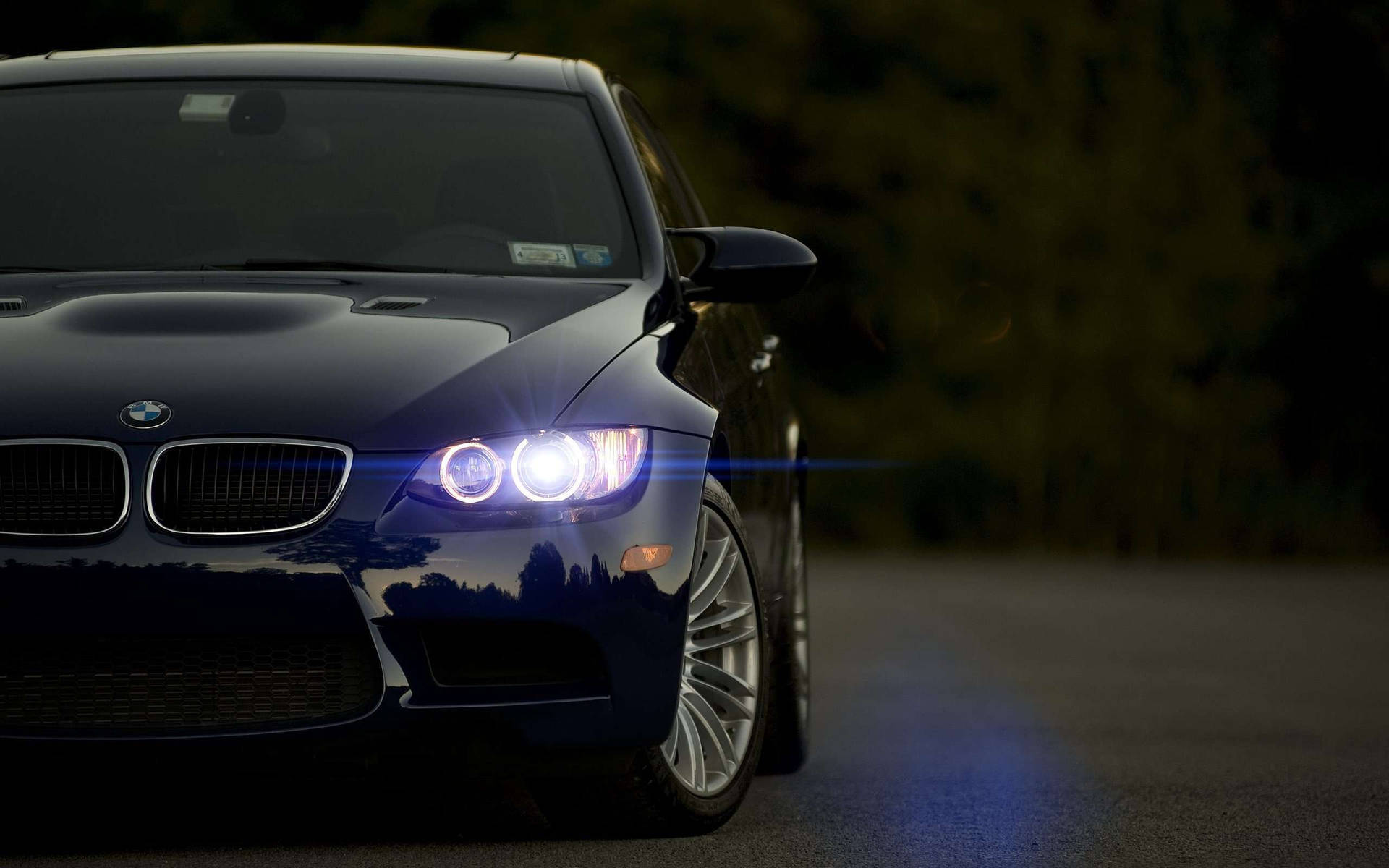 黑色BMW跑車在夜間道路上亮著車頭燈。