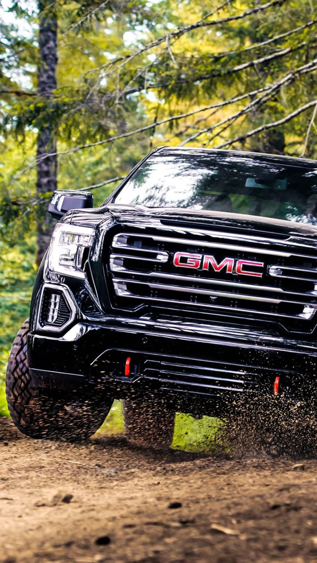Gmc Yukon 桌布 壁紙 — 一輛黑色GMC卡車在明亮的森林陽光下，在泥濘地形上行駛，泥土四濺。