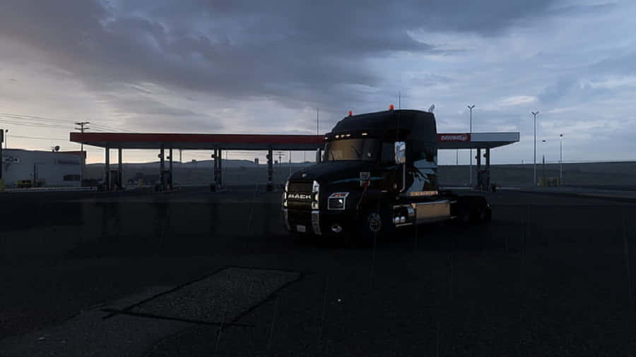 Simulation Games 桌布 壁紙 — 一輛黑色Mack貨車停泊在加油站，背景是帶有烏雲的暮色天空。