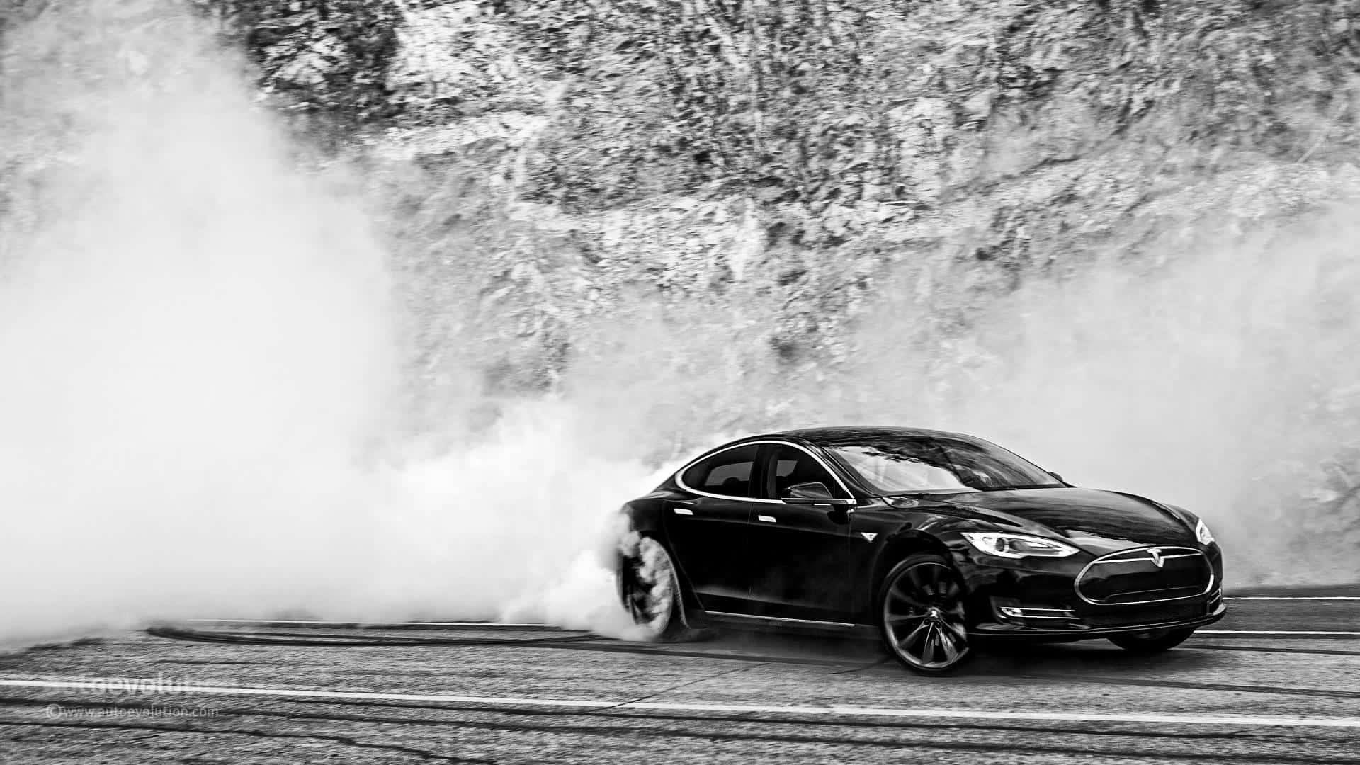 tesla 桌布 壁紙 — 一輛黑色Tesla在積雪的山路上進行戲劇性的飄移，揚起濃煙。