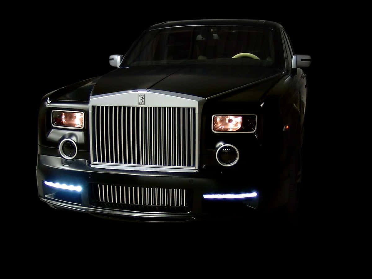 Rolls Royce 桌布 壁紙 — 一輛黑色勞斯萊斯幻影在攝影棚燈光下閃耀，配以發光的頭燈和鍍鉻格柵，背景為純黑色。