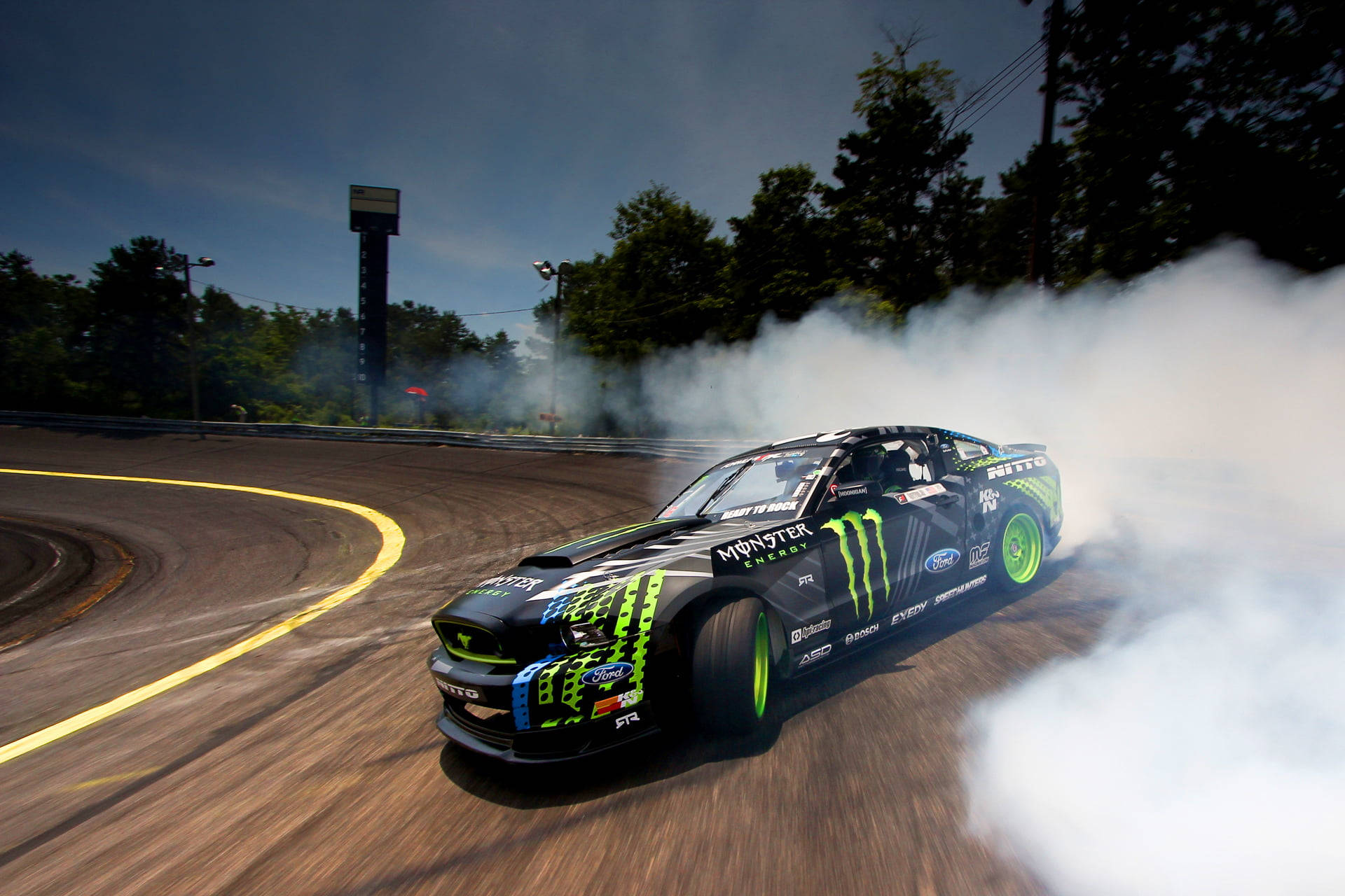Ford 桌布 壁紙 — 一輛黑色和綠色的Monster Energy Ford Mustang在賽道彎位飄移，在陰天天空下揚起濃厚白煙。