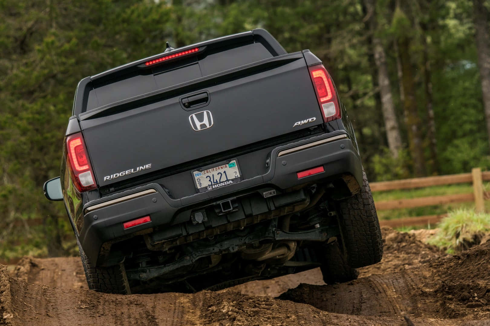 Honda Ridgeline 桌布 壁紙 — 一輛黑色本田Ridgeline AWD卡車正在被茂密綠色森林包圍的泥濘土丘上激進地攀爬。