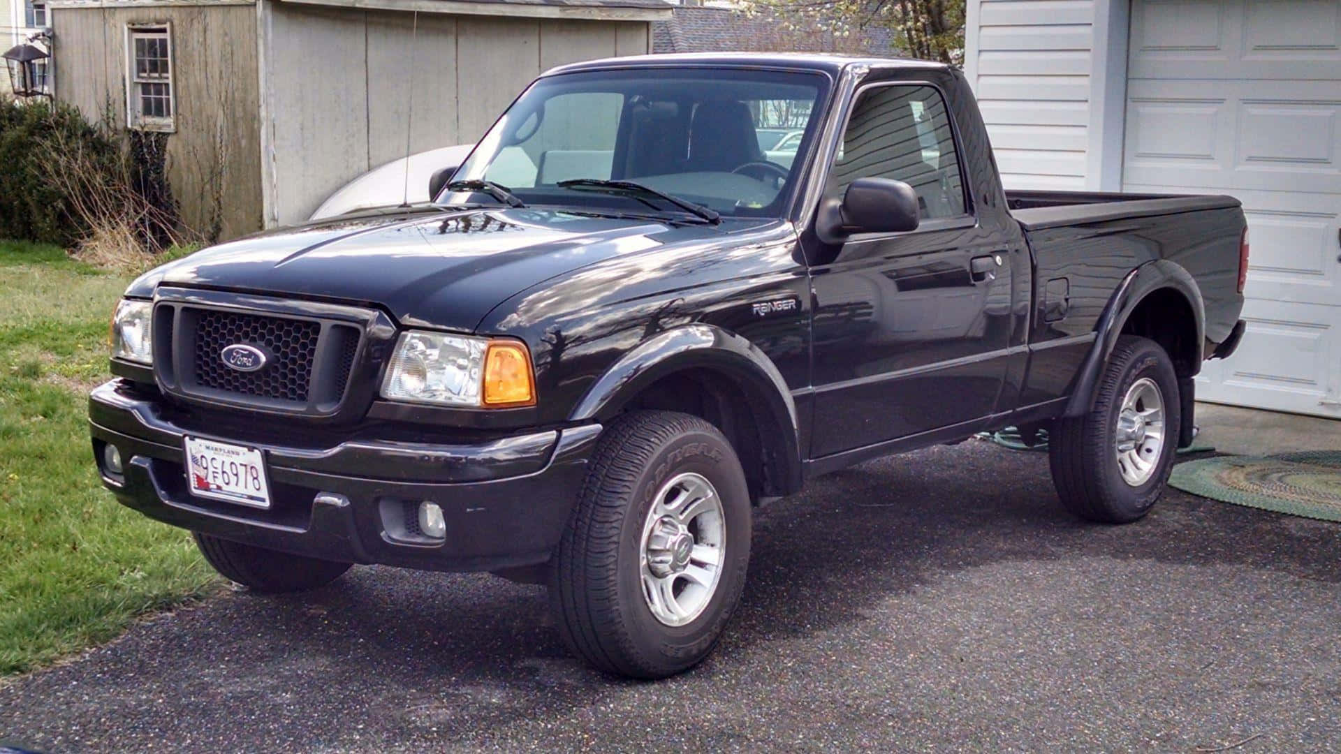 Ford Ranger 桌布 壁紙 — 一輛黑色福特Ranger pickup貨車停泊在碎石車道上，旁邊是白色車庫，背景有綠色草地和木棚。