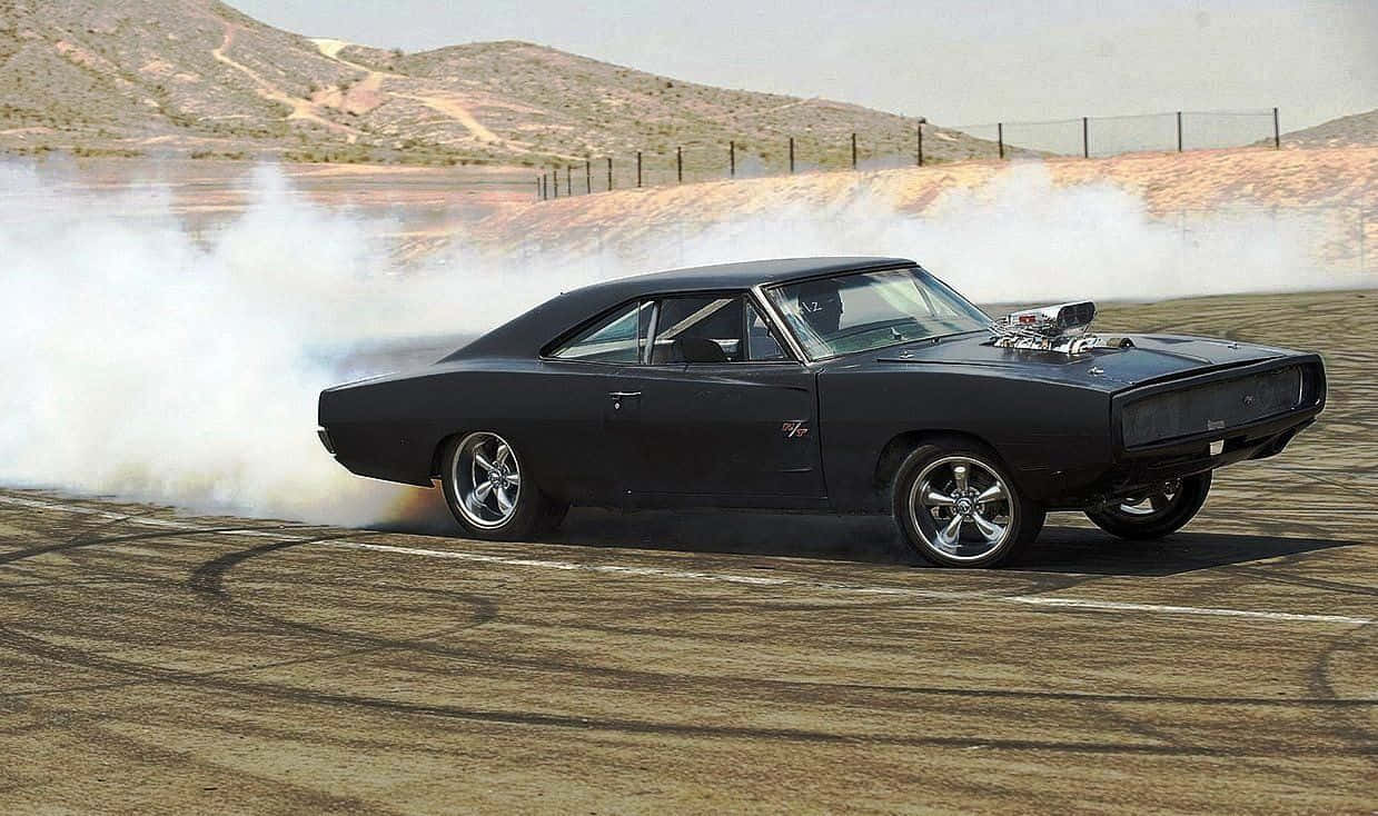 Dodge Charger 桌布 壁紙 — 一輛黑色經典肌肉車在塵土飛揚的沙漠賽道上燒胎，揚起濃厚的白煙。