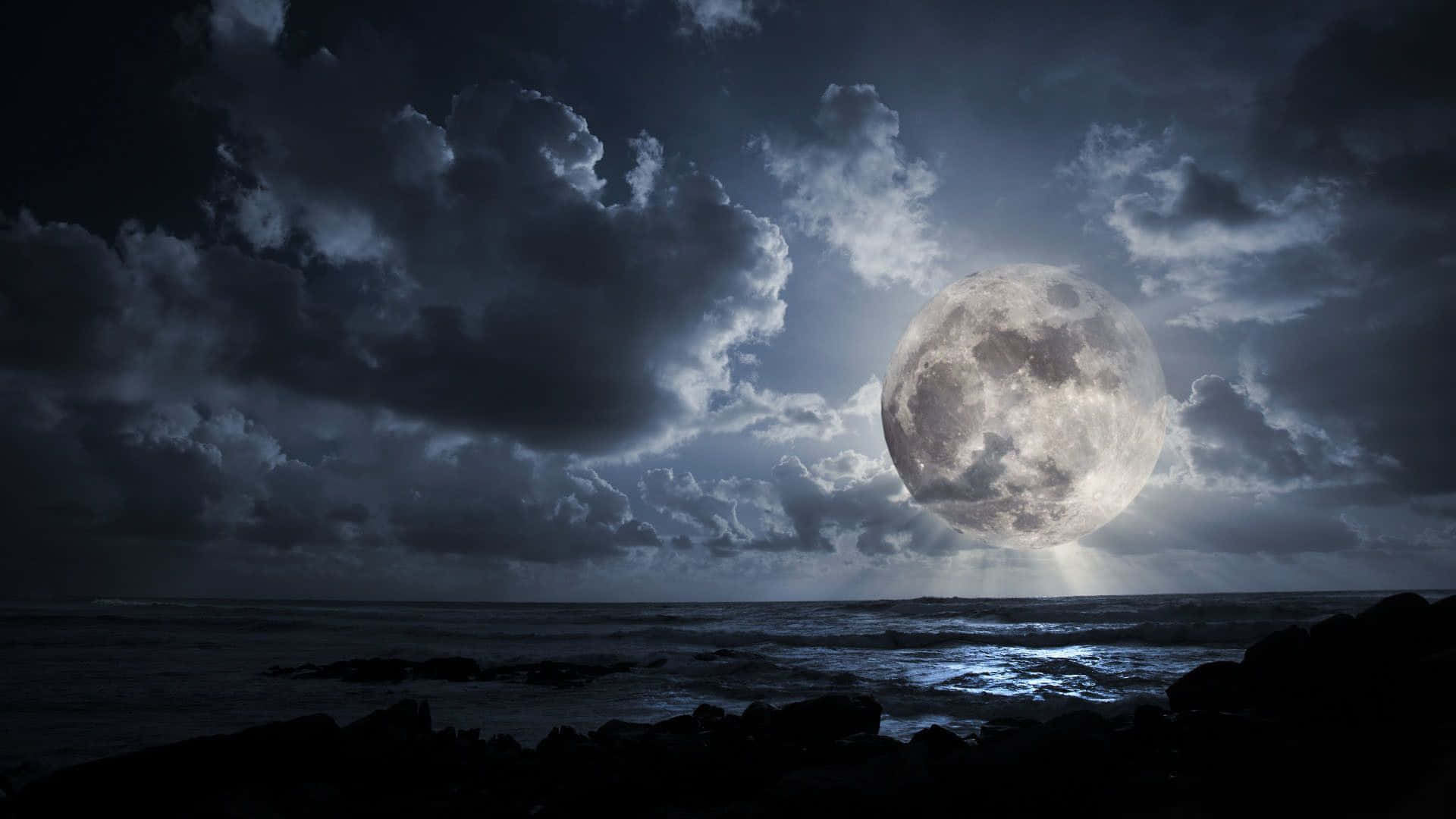 Dark Moon 桌布 壁紙 — 一輪巨大的發光月亮穿透黑暗的暴風雲，照耀在夜晚洶湧的海洋之上。