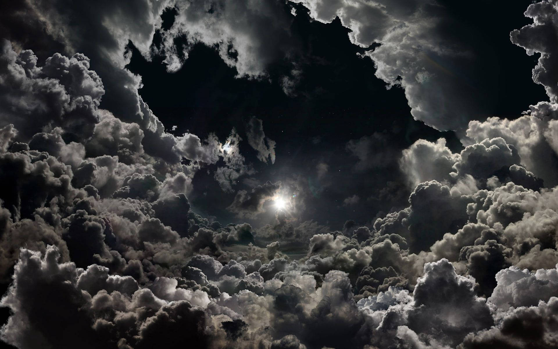 雲朵 桌布 壁紙 — 一輪戲劇性的月亮穿過由深色和淺色雲朵組成的濃密樹冠，在充滿氛圍的夜空中閃耀。