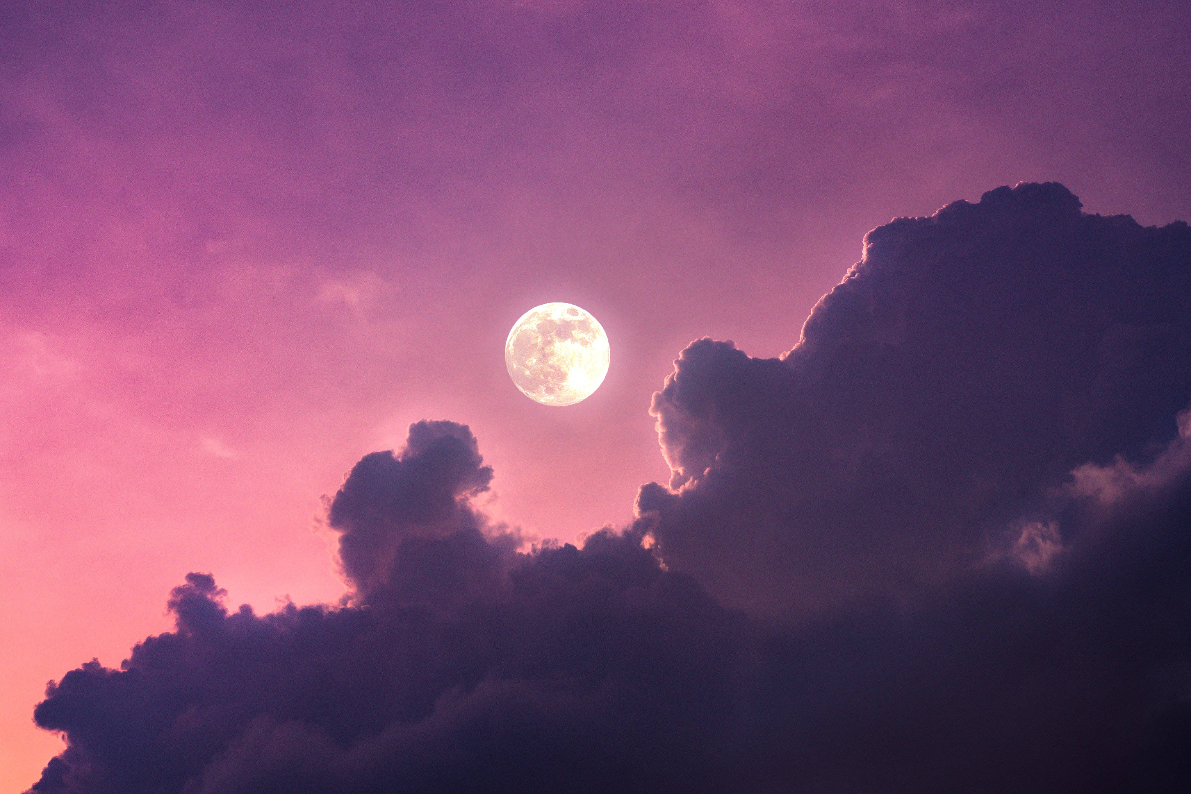 full moon 桌布 壁紙 — 一輪明亮的滿月在暮色天空中透過戲劇性的紫色和粉紅色雲層發光。