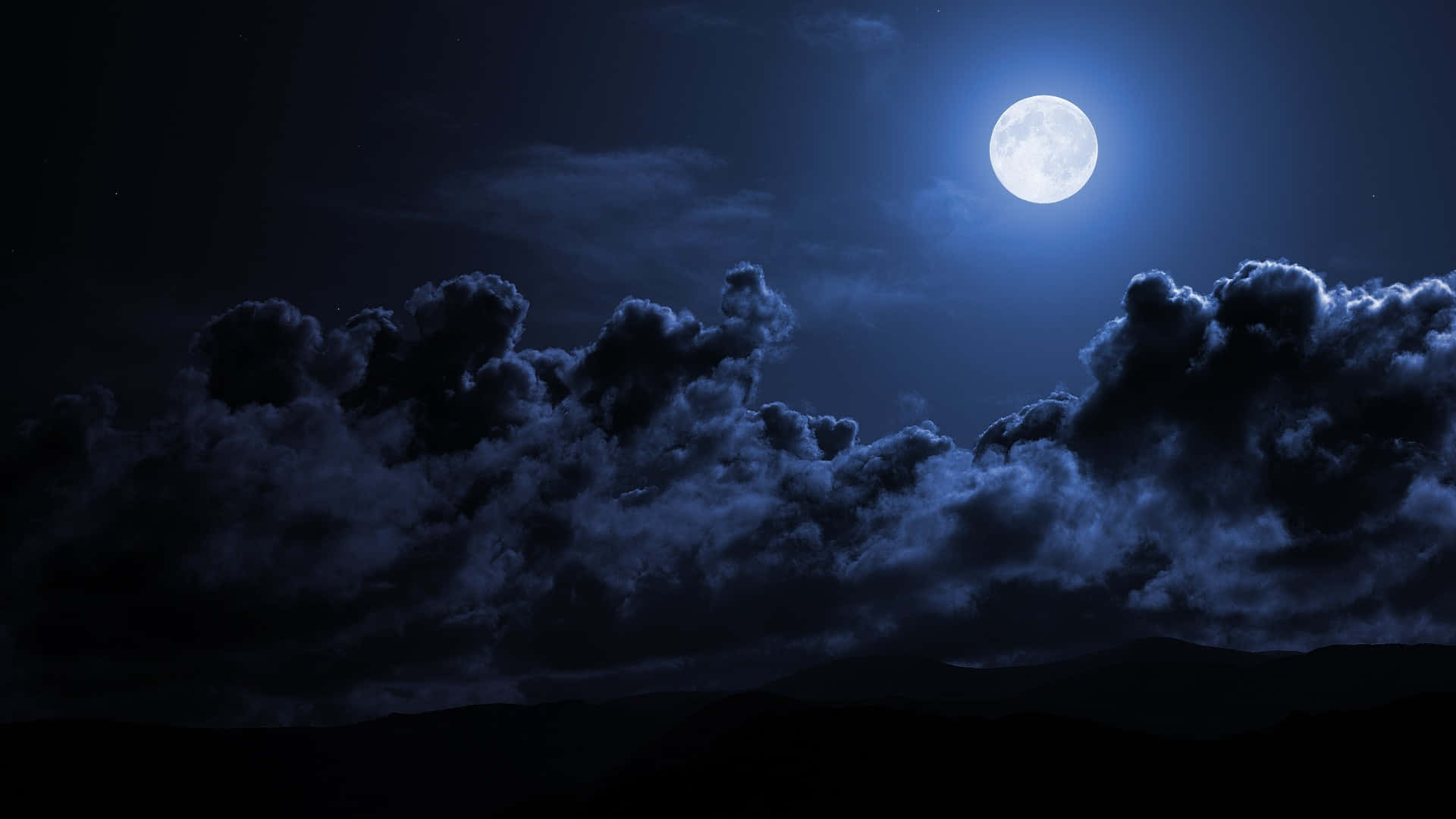 Moon Night 桌布 壁紙 — 一輪明亮的滿月在無星的夜空下，將清冷的光芒投射在戲劇性的烏雲和遠山輪廓上。