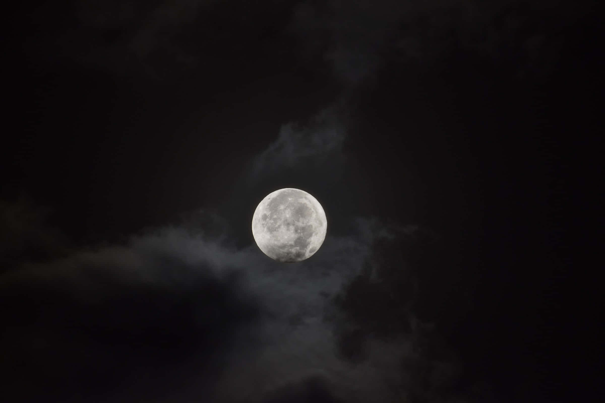 Dark Moon 桌布 壁紙 — 一輪明亮的滿月穿過旋轉的烏雲，在深邃的夜空中閃耀。