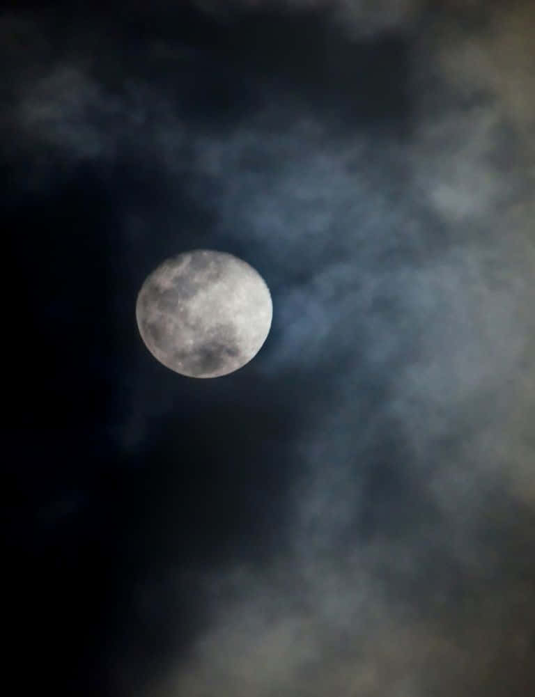 Dark Moon 桌布 壁紙 — 一輪明亮的滿月穿過旋轉的烏雲，在陰鬱的夜空中閃耀。