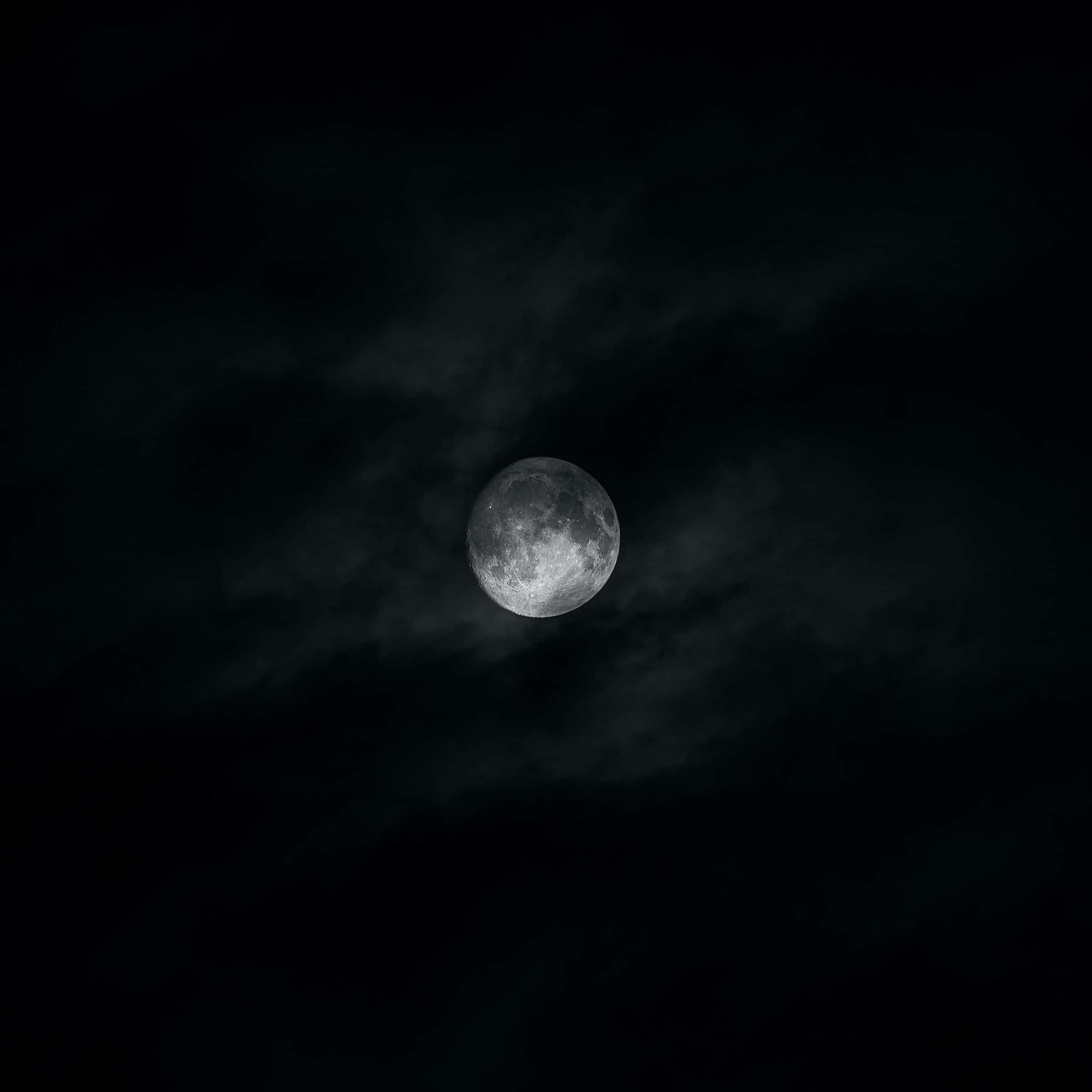 Dark Moon 桌布 壁紙 — 一輪明亮的滿月穿過旋轉的烏雲，在清冷的夜空中閃耀。