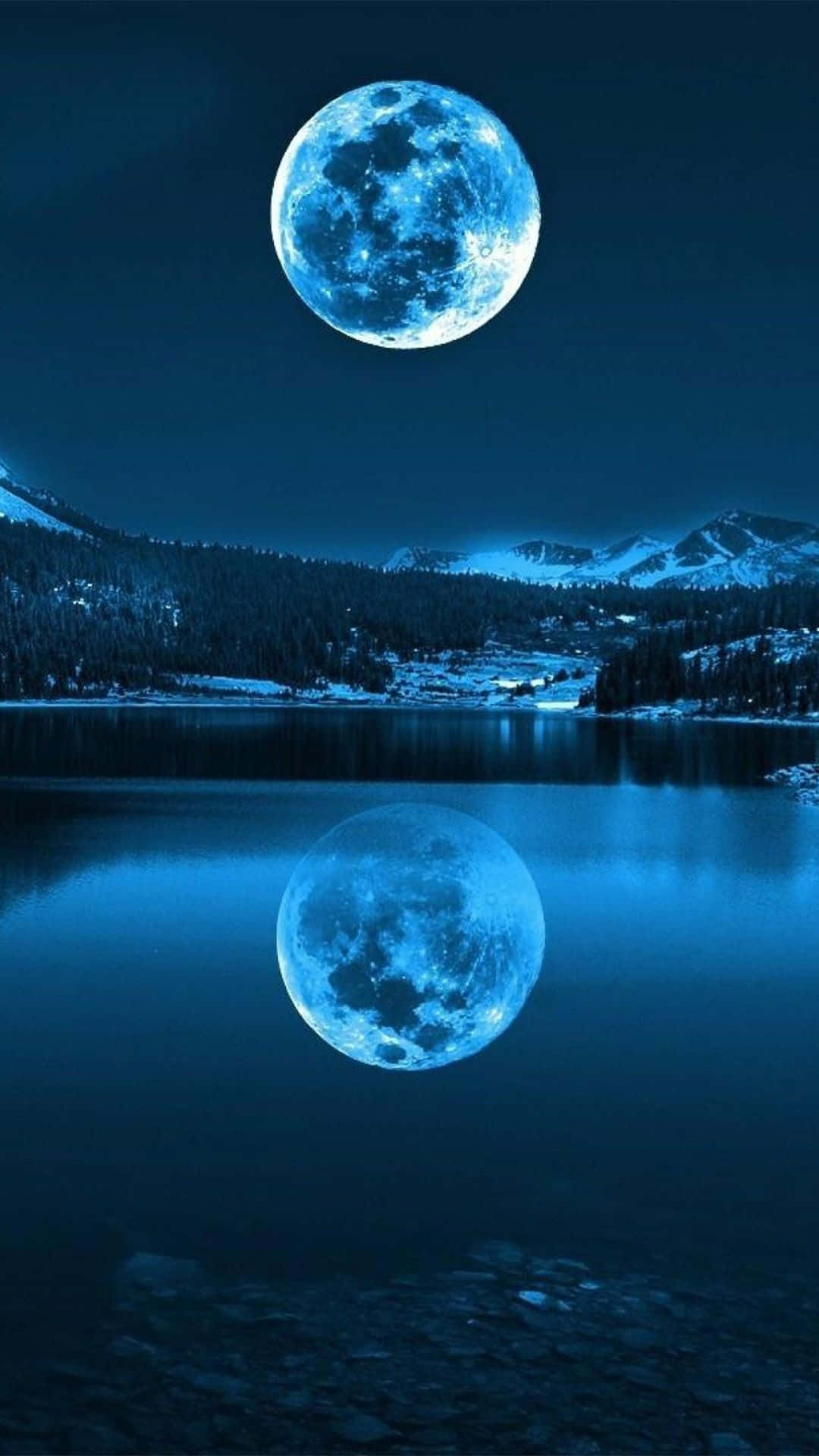 Smartphone 桌布 壁紙 — 一輪明亮的藍月懸掛在積雪的山脈之上，在深藍色夜空下完美地倒映在平靜的湖面上。